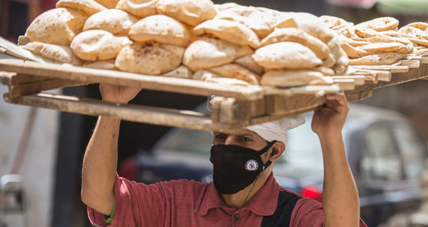 مصري يحمل خبزاً طازجاً في أحد أحياء القاهرة أمس (إ.ب.أ)