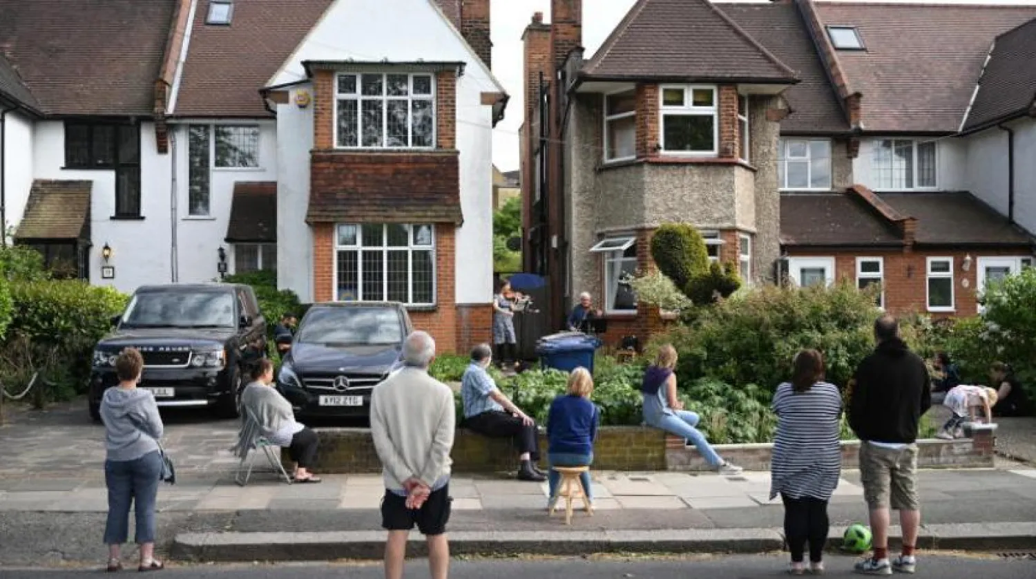 Bazı insanlar Kuzey Londra'da sokaklarında verilen konseri takip ediyor (EPA)
