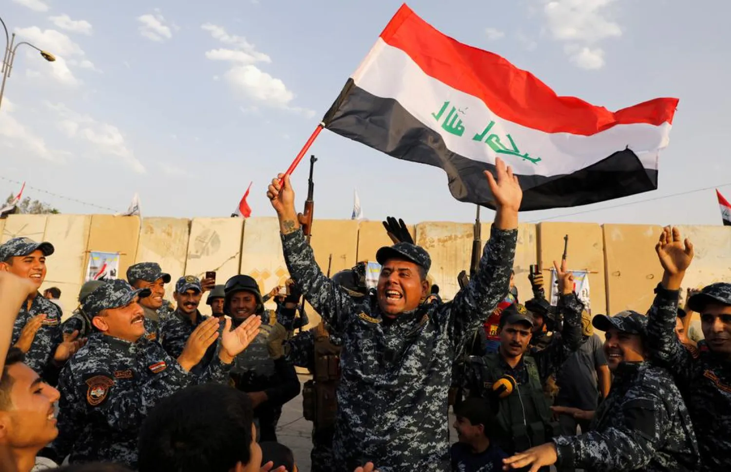 A member of Iraqi Federal Police waves an Iraqi flag as they celebrate victory of military operations against ISIS militants in West Mosul. (Reuters file photo)