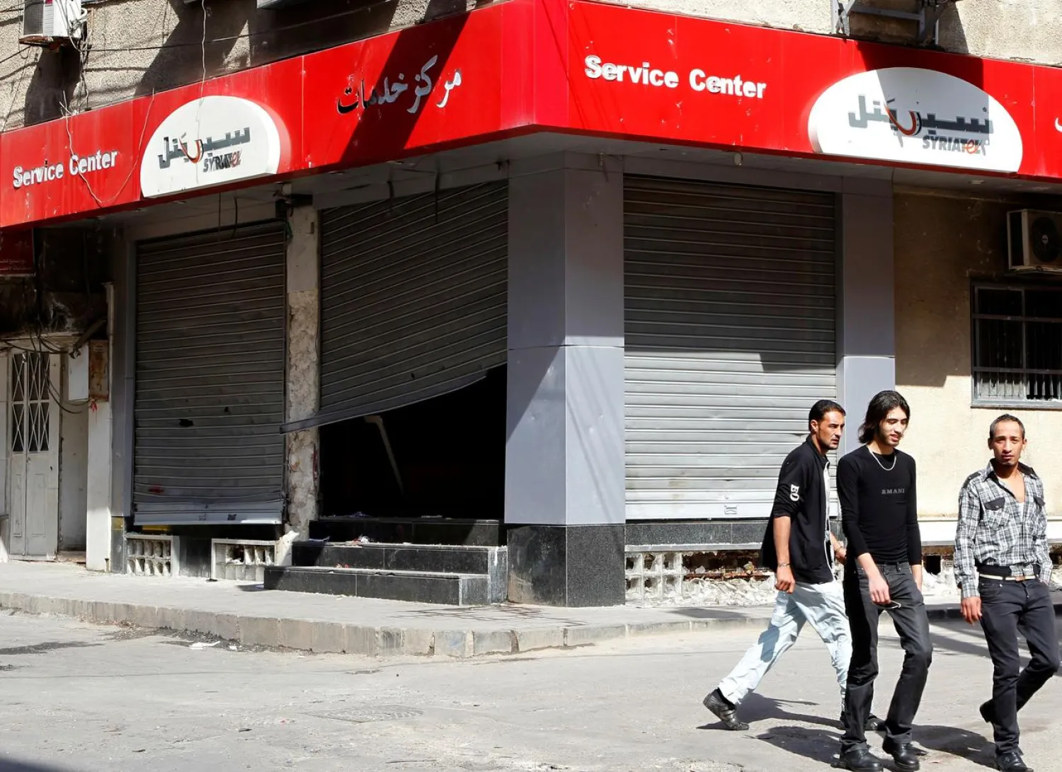 People walk past the of cellphone company Syriatel, which is owned by Rami Makhlouf (File photo: Reuters)