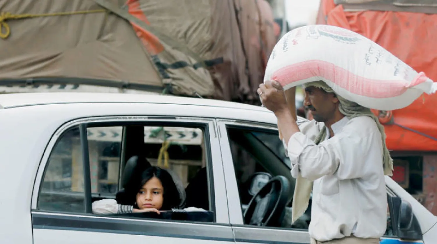 رجل يحمل كيس طحين فوق رأسه بأحد شوارع صنعاء (رويترز)