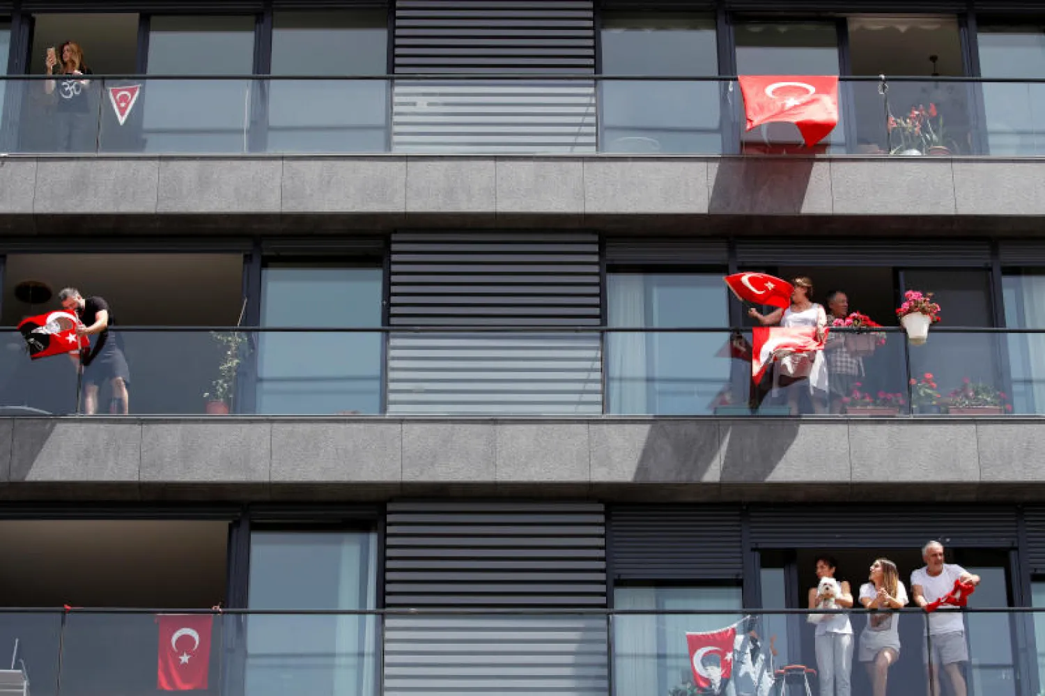 أتراك يمسكون بأعلام بلادهم في الشرفات خلال الاحتفال بيوم الشباب والرياضة في إسطنبول (رويترز)