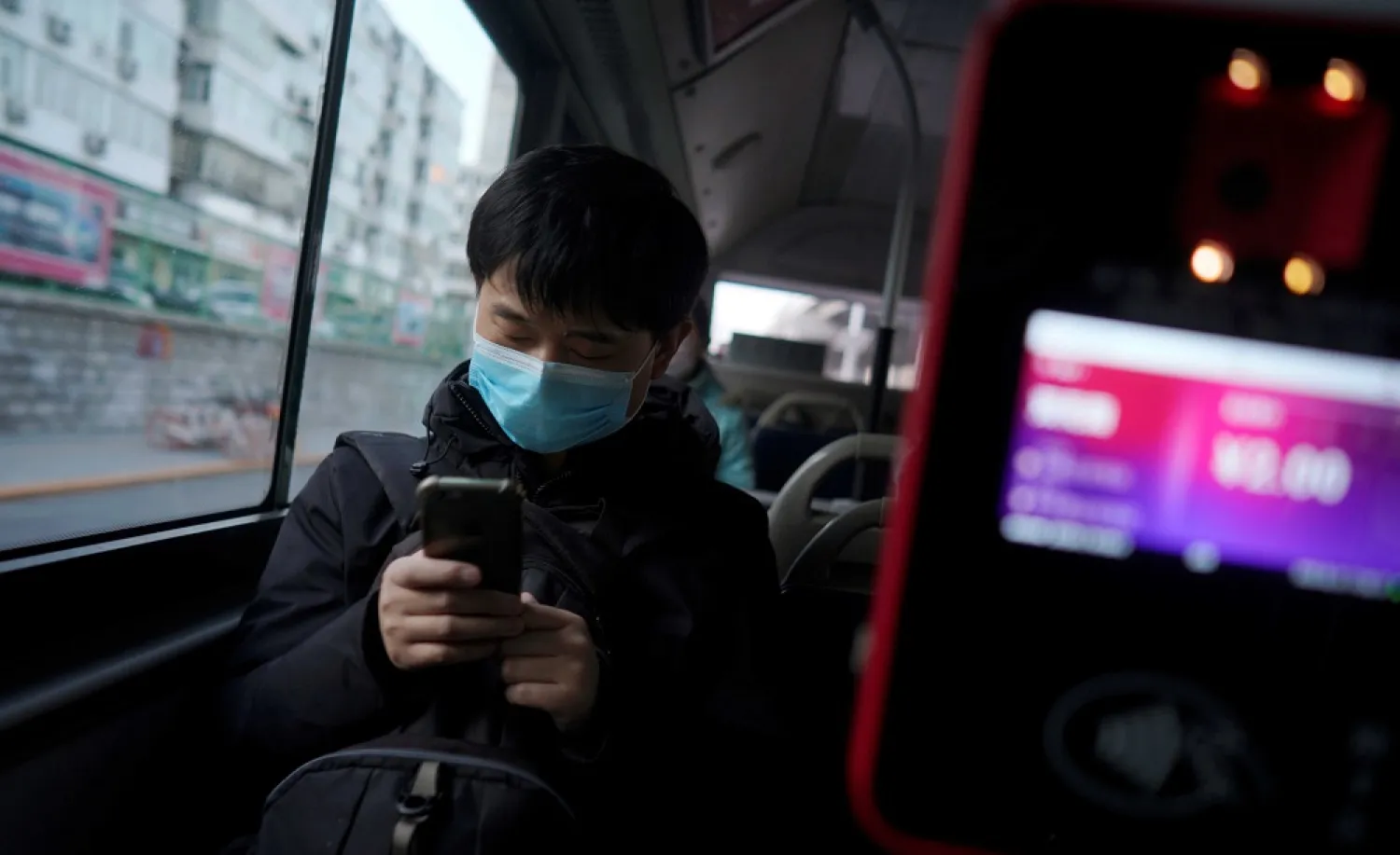 A passenger wearing a face mask checks his mobile phone on a bus, following an outbreak of the novel coronavirus in the country, in Beijing, China, Feb. 21, 2020. (Reuters)
