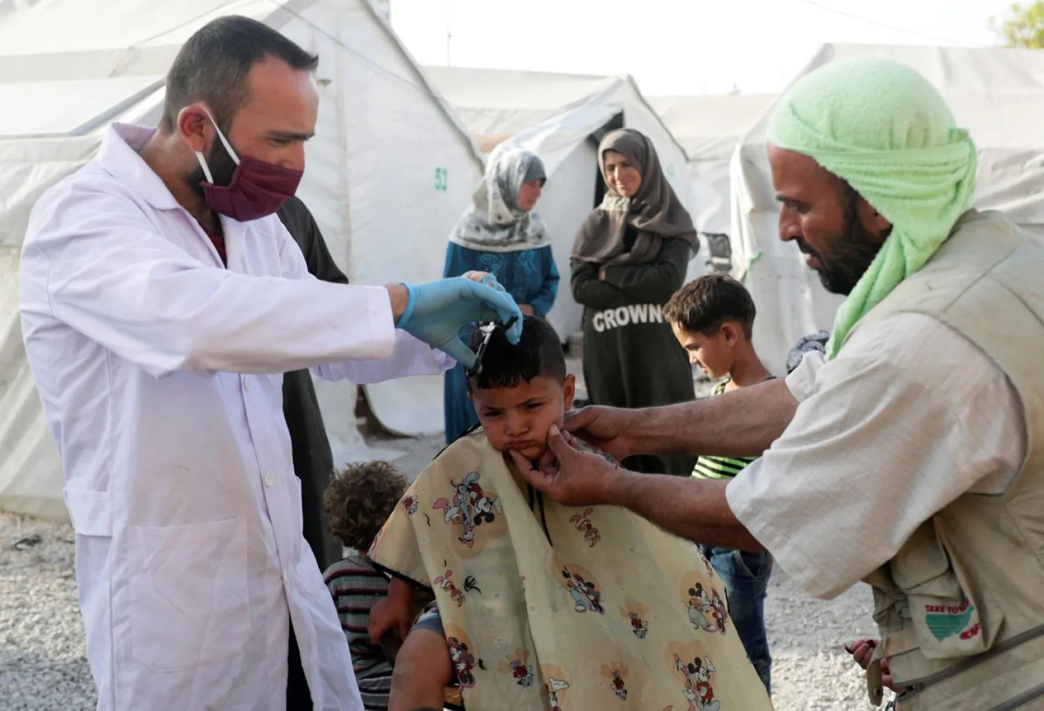 A volunteer hairdresser cuts the hair of an internally displaced boy, ahead of the Eid al-Fitr holiday, amid concerns over the spread of the coronavirus, at an IDP camp in Idlib, Syria May 19, 2020. (Reuters)