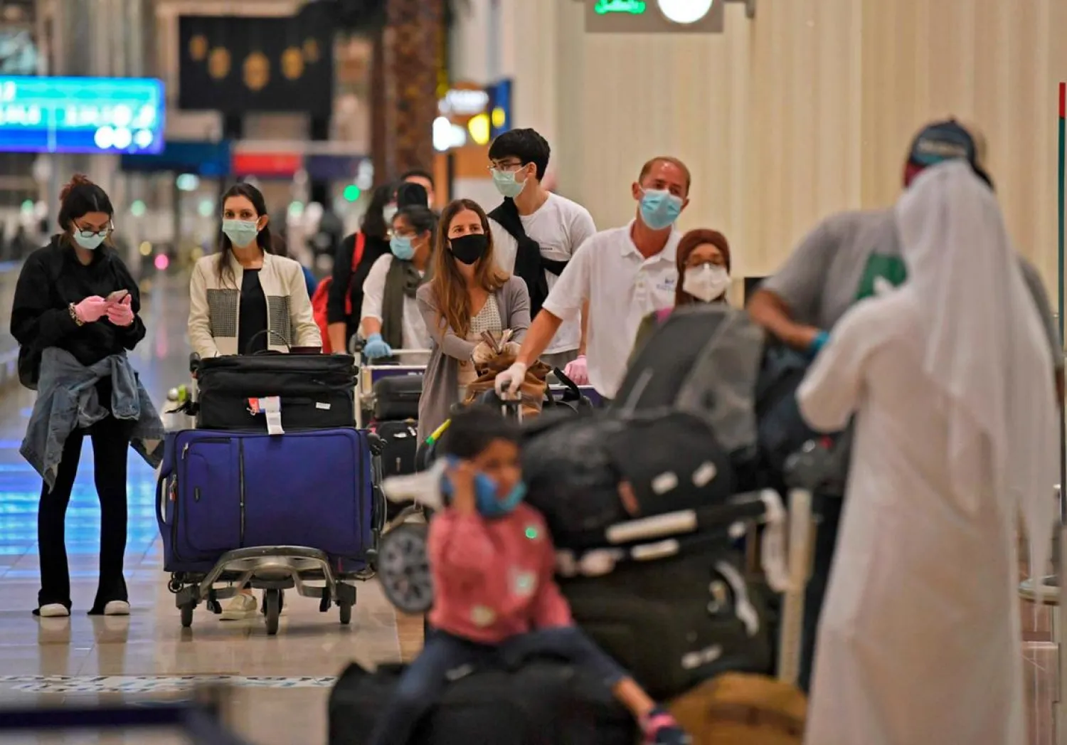 Passengers from an Emirates flight from London queue before being checked by health workers at Dubai International Airport on May 8. (AFP)