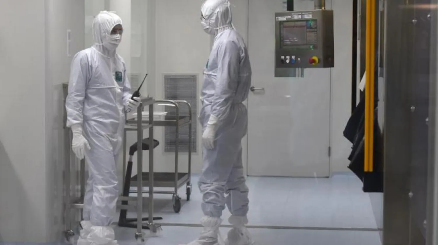 Rus Biyoteknoloji Şirketi üretim hattında koruyucu ekipman giyen çalışanlar (AFP)
