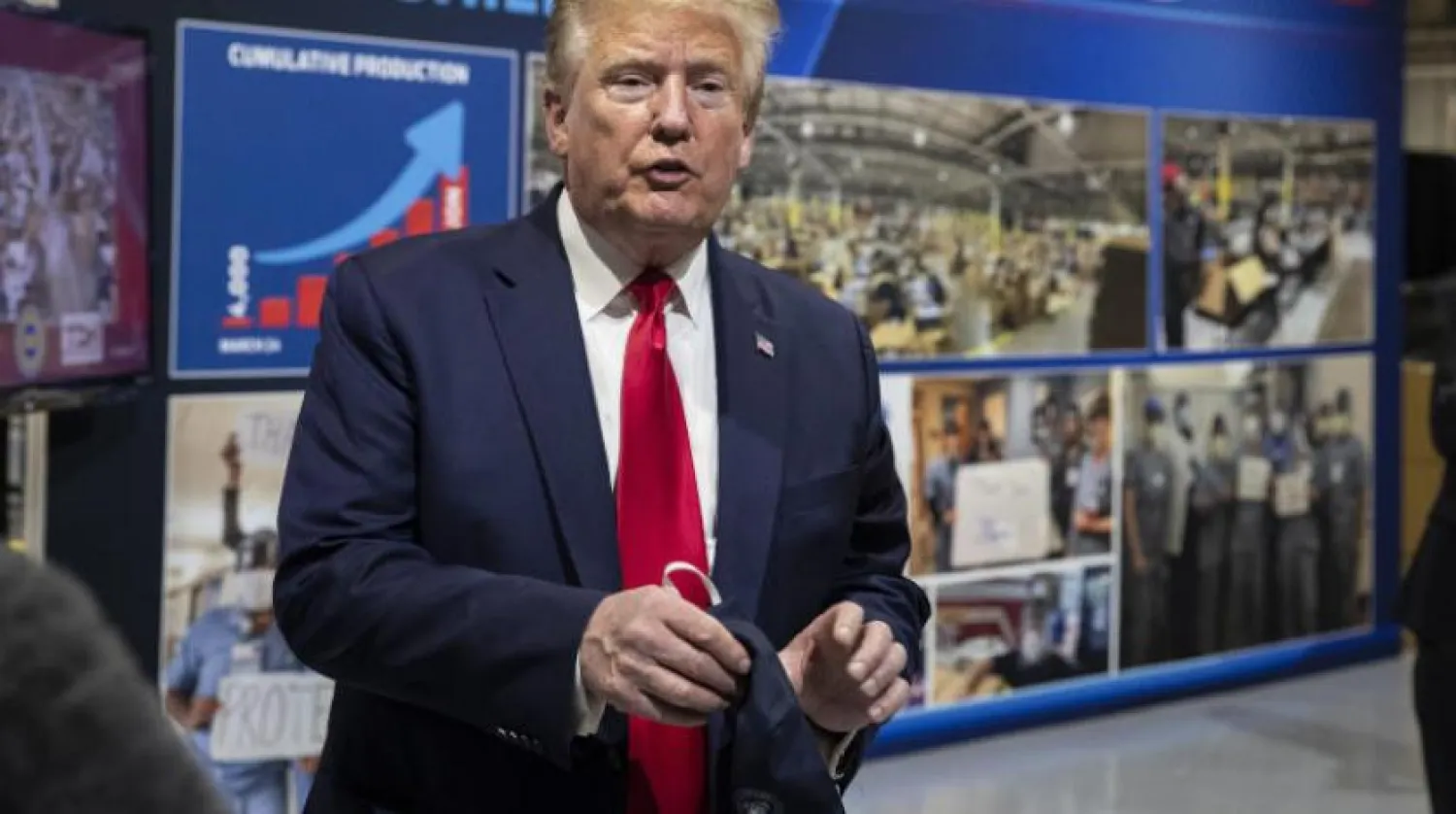 ABD Başkanı Donald Trump, Ford fabrikasını ziyareti sırasında maskesini elinde tutarken (AP)