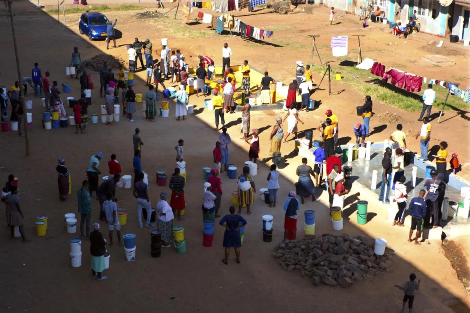 In this April, 24, 2020, photo, people wait to fetch water from a row of communal taps that the group Doctors Without Borders provided in a suburb of Harare, Zimbabwe. (AP Photo/Tsvangirayi Mukwazhi)
