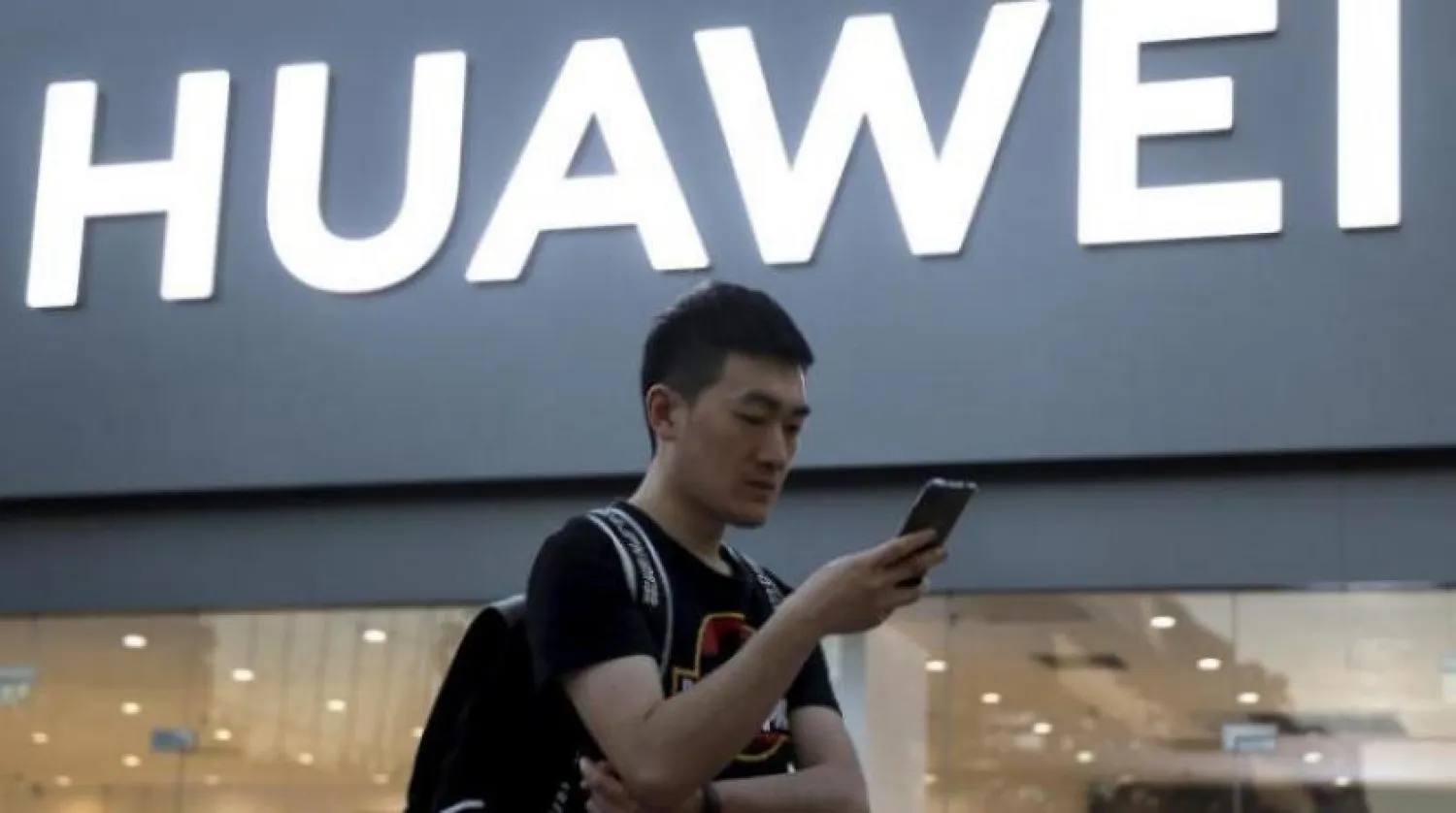 Pekin’de bir adam Huawei mağazasının önünde dururken (Arşiv-AP)