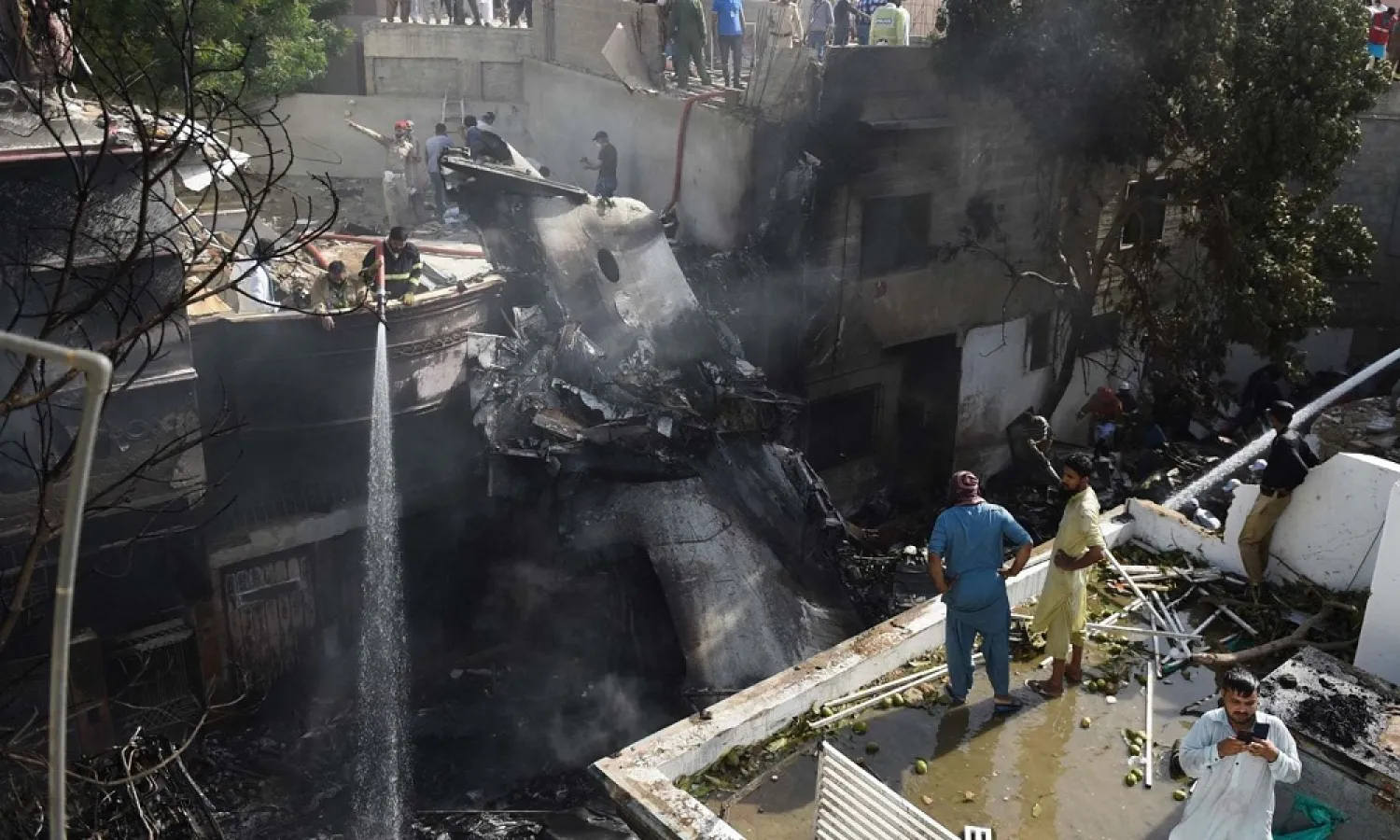 Firefighters spray water on the wreckage of a plane the crashed in a residential area in Karachi on May 22, 2020. (AFP)