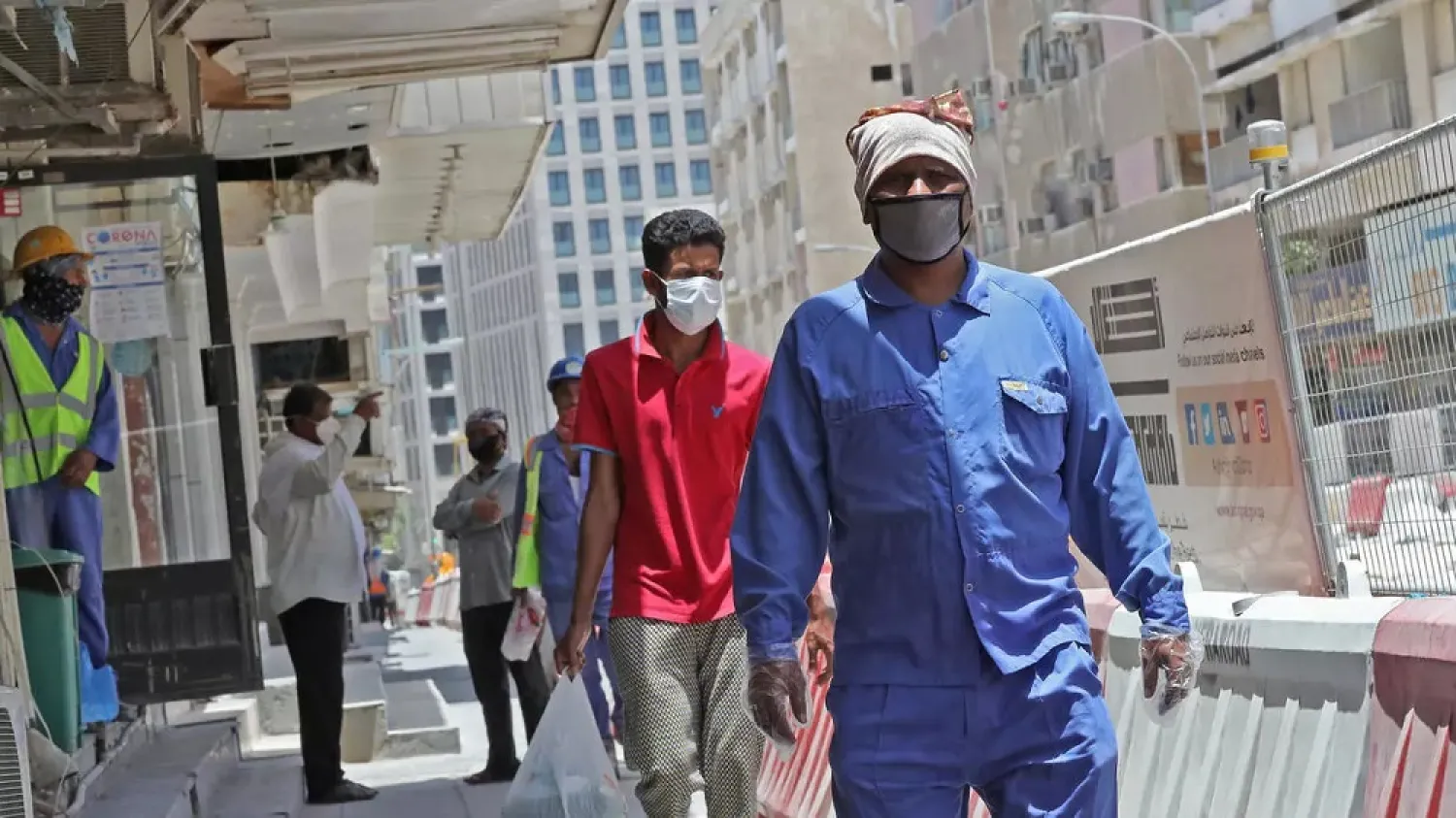 Workers wearing protective masks walk by on a street in Qatar's capital Doha. (AFP)