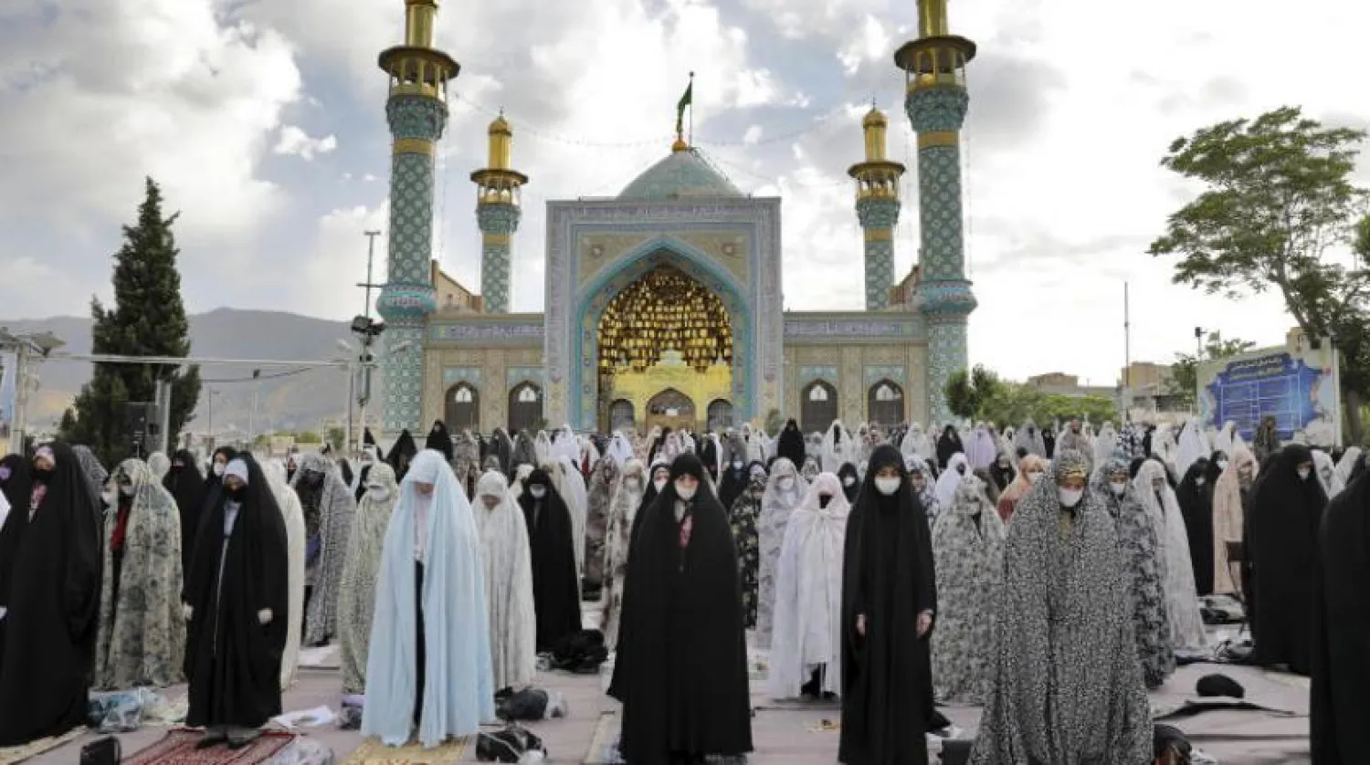 Worshippers wearing protective face masks and gloves offer Eid al-Fitr prayers outside a shrine to help prevent the spread of the coronavirus, in Tehran, Iran, Sunday, May 24, 2020. (AP Photo/Ebrahim Noroozi)