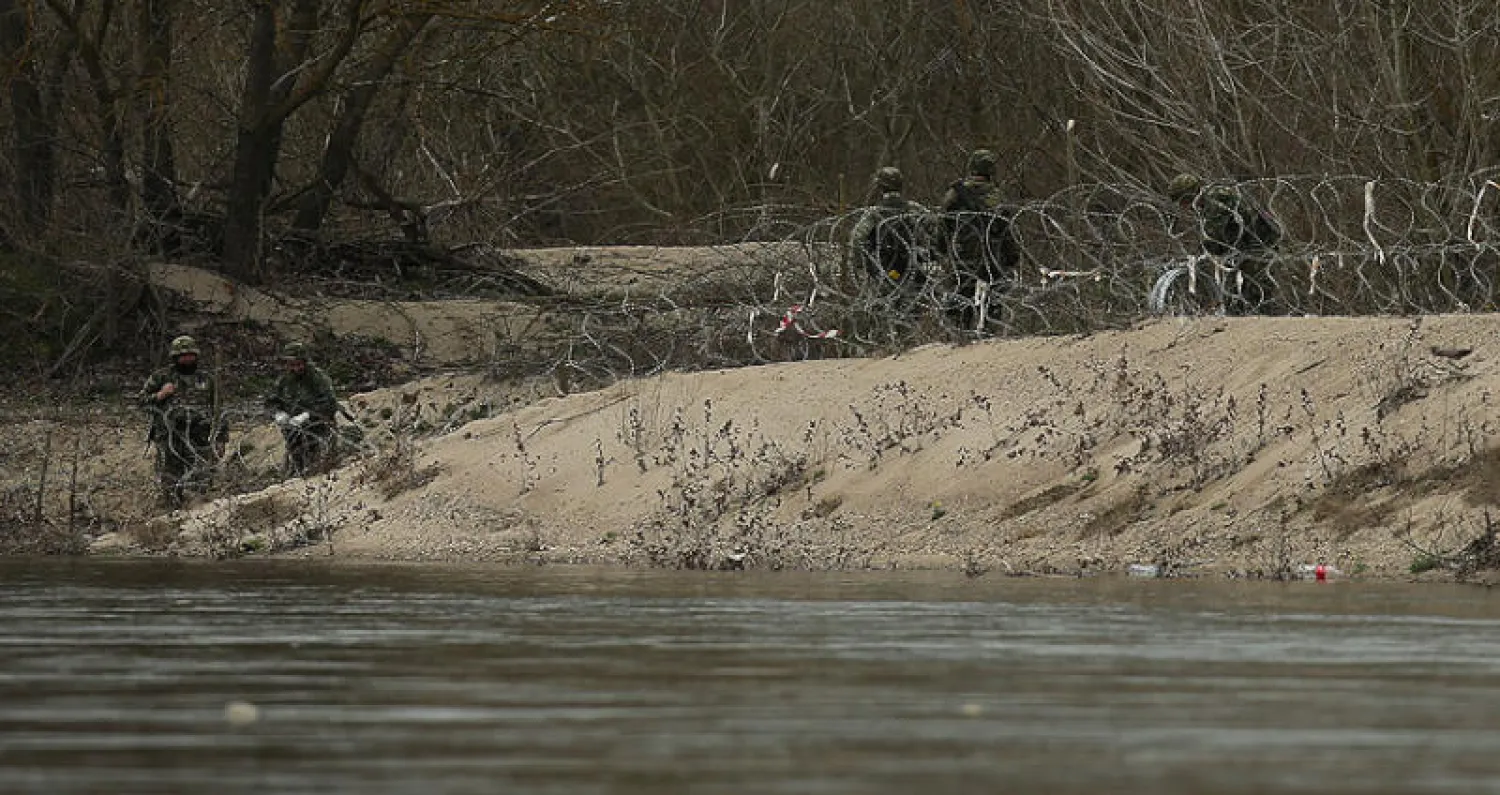 جنود يونانيون ينشرون أسلاكاً شائكة على السياج الحدودي على ضفة نهر ماريتسا في مارس الماضي (أ.ف.ب)