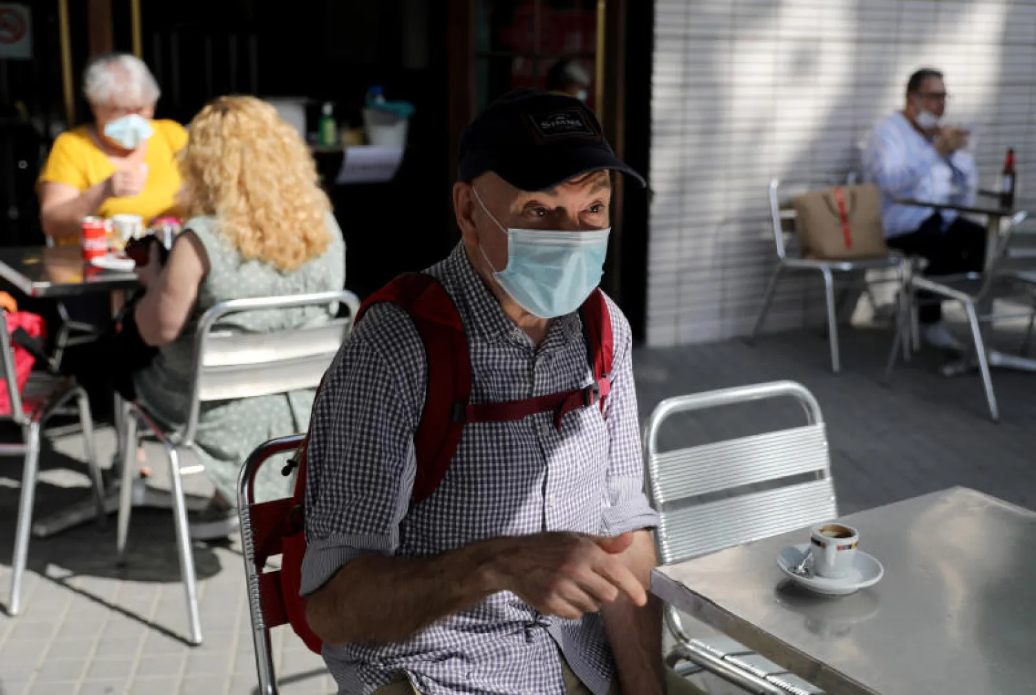 رجل يضع قناع الوجه الواقي خارج مقهى في زيوريخ (رويترز)