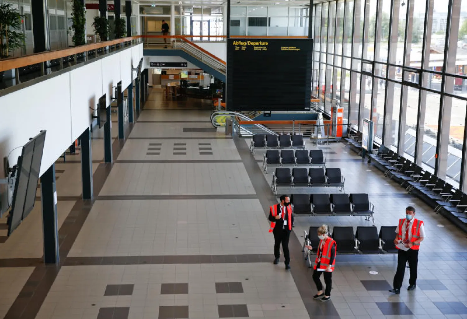 موظفون في قاعة مغادرة فارغة في مطار برلين شونفيلد (رويترز)