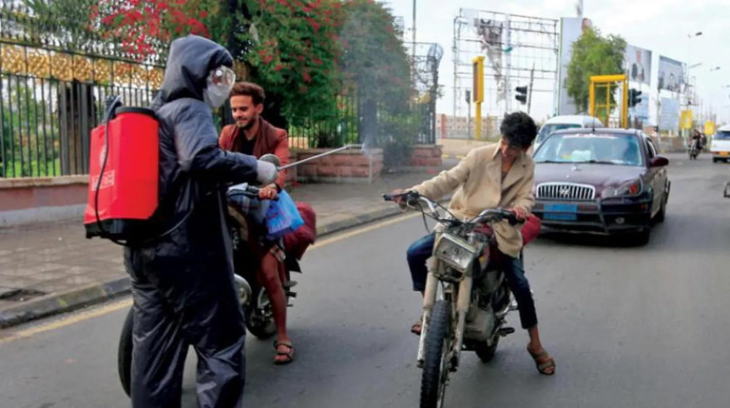 Houthi security officer spraying sterilization spray to passers-by in Sanaa (AFP)

