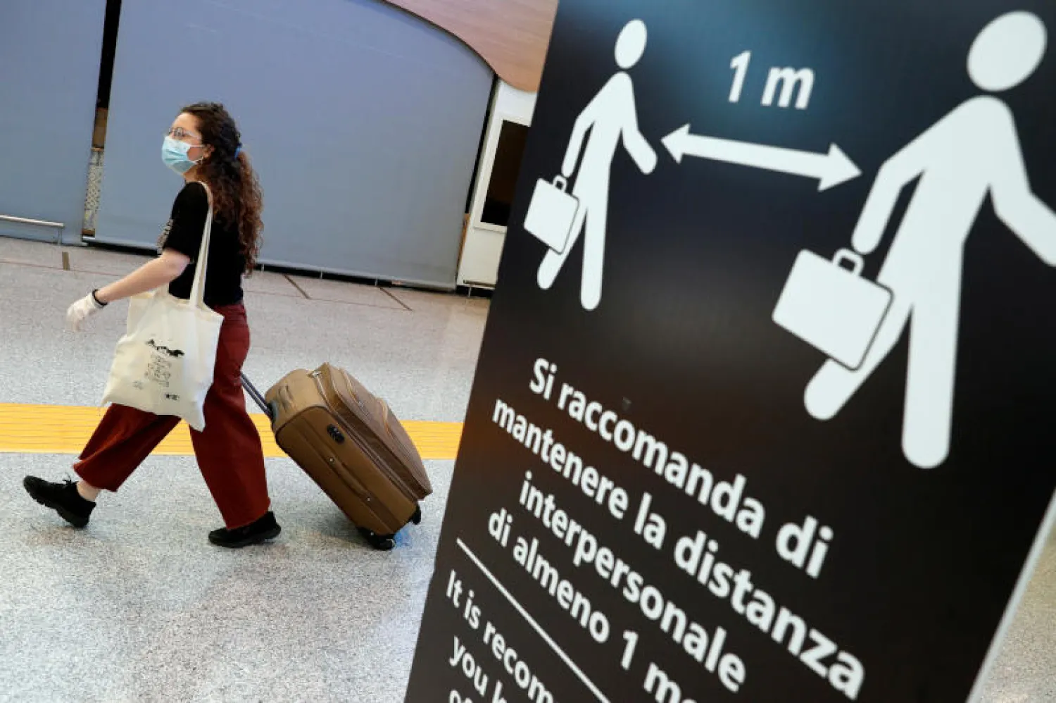 مسافرة تضع كمامة في مطار فيوميتشينو بروما في إيطاليا (رويترز)