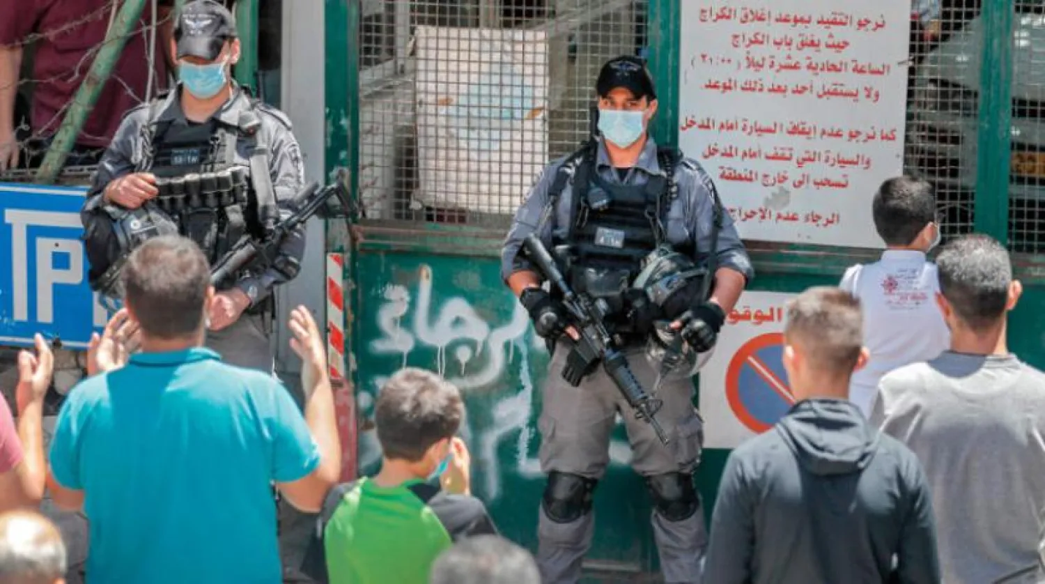 Yarından (Pazar) itibaren kapılarının yeniden ibadete açılması kararlaştırılan Mescid-i Aksa yakınında namaz kılmaya hazırlanan Filistinlilerin önünde duran İsrailli iki güvenlik görevlisi (AFP)