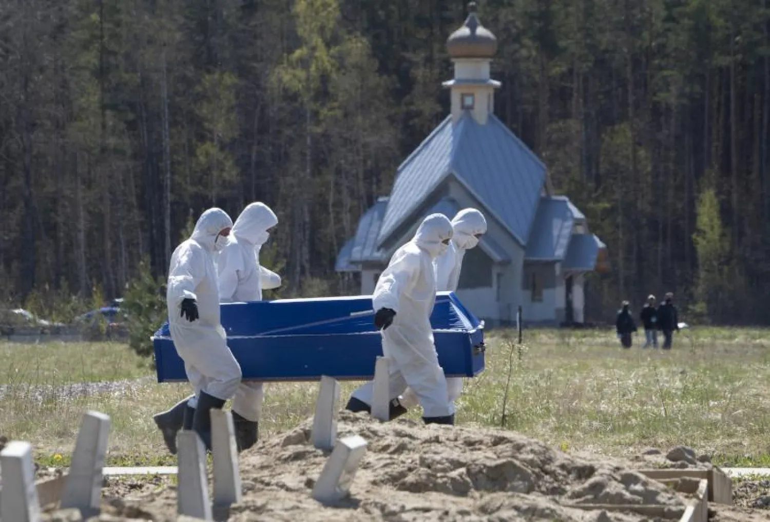 عمال يرتدون البدلات الواقية أثناء توجههم لدفن أحد ضحايا فيروس كورونا في روسيا (أ.ب)