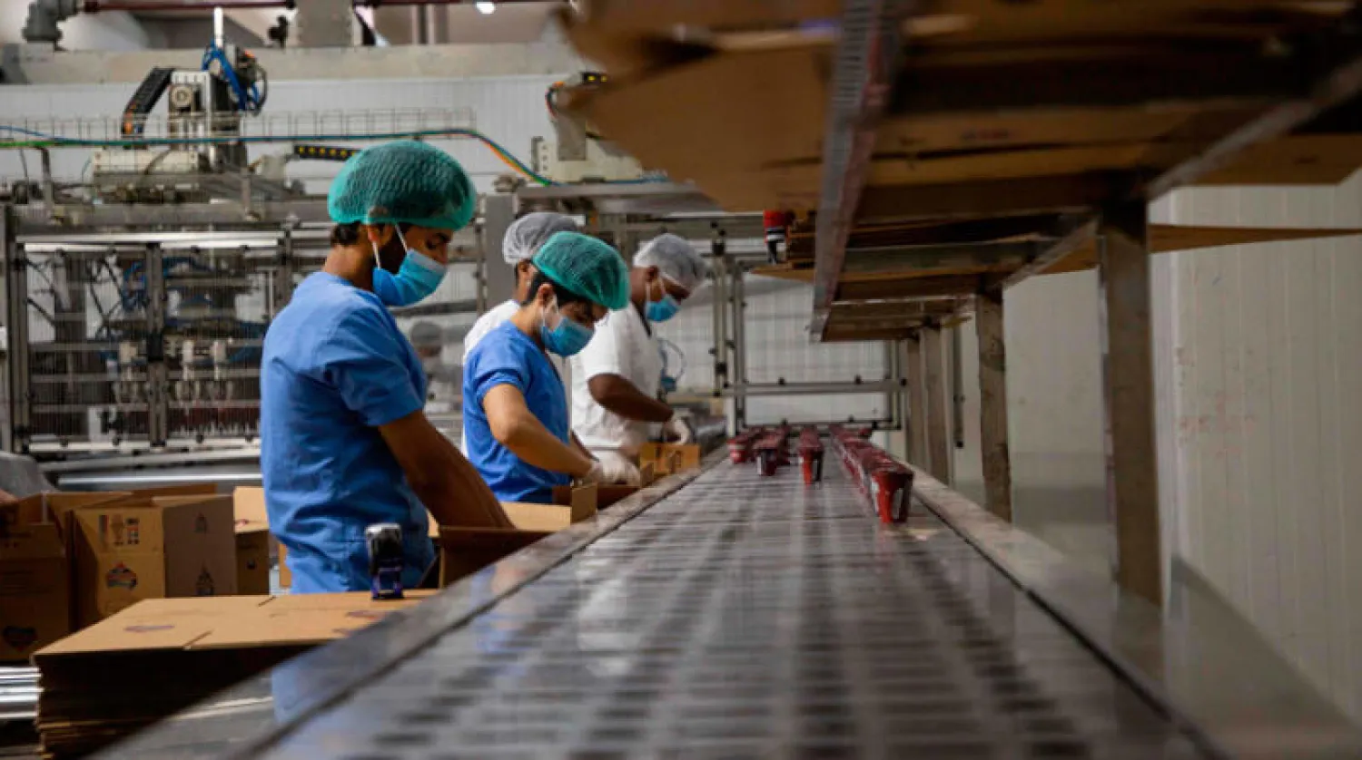 عمال عراقيون يضعون كمامات في أحد مصانع البصرة (أ.ف.ب)