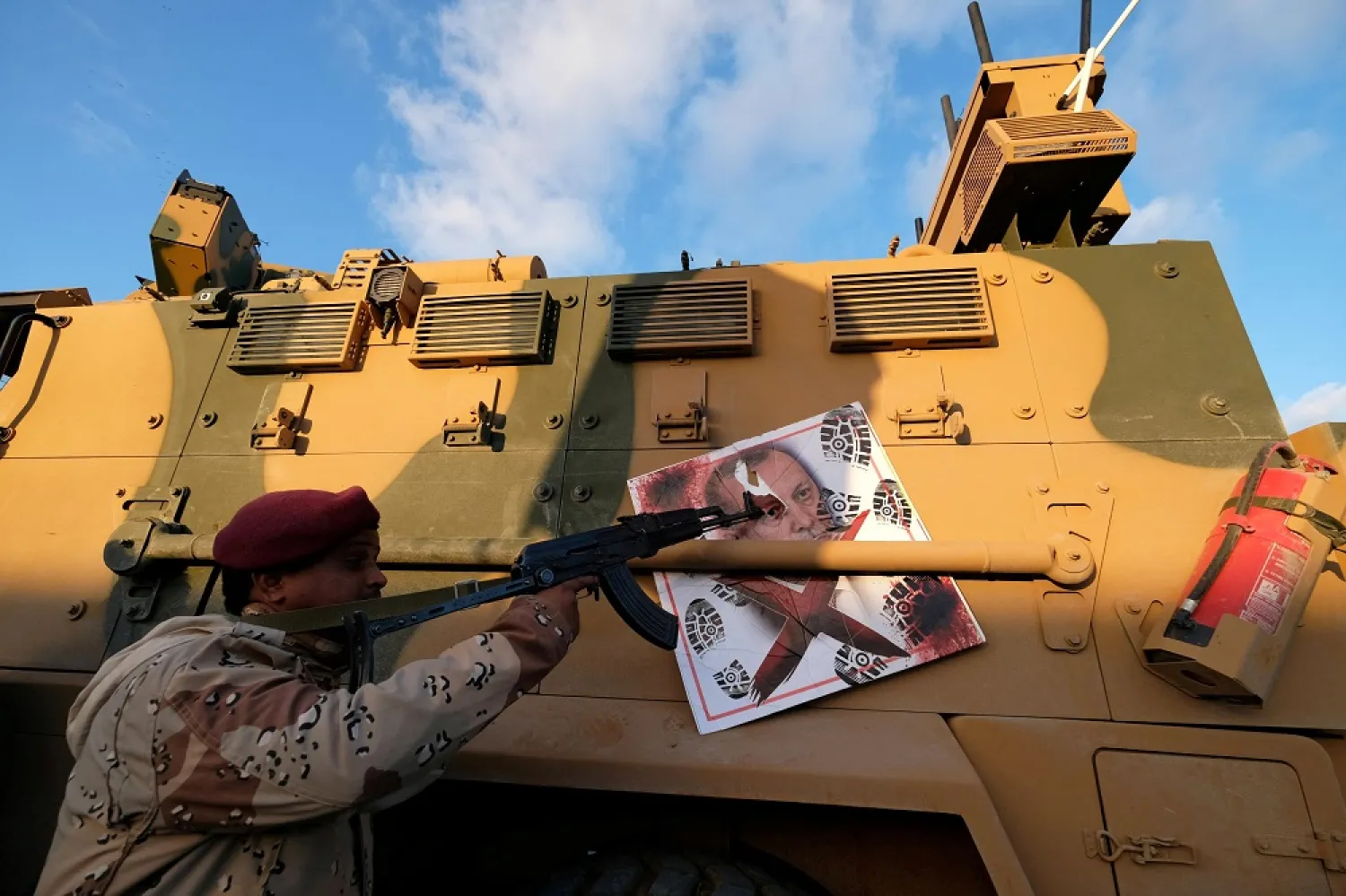 An LNA member points his gun to the image of Turkish President Erdogan hanged on a Turkish military armored vehicle, in Benghazi, Libya January 28, 2020. (Reuters)