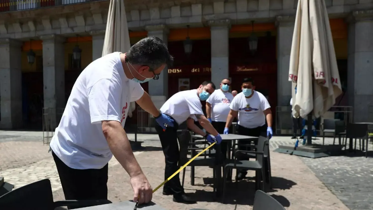 Workers use measuring tape to check social distancing as they set up a terrace, amid the coronavirus outbreak, in Madrid, Spain, May 24, 2020. (Reuters)