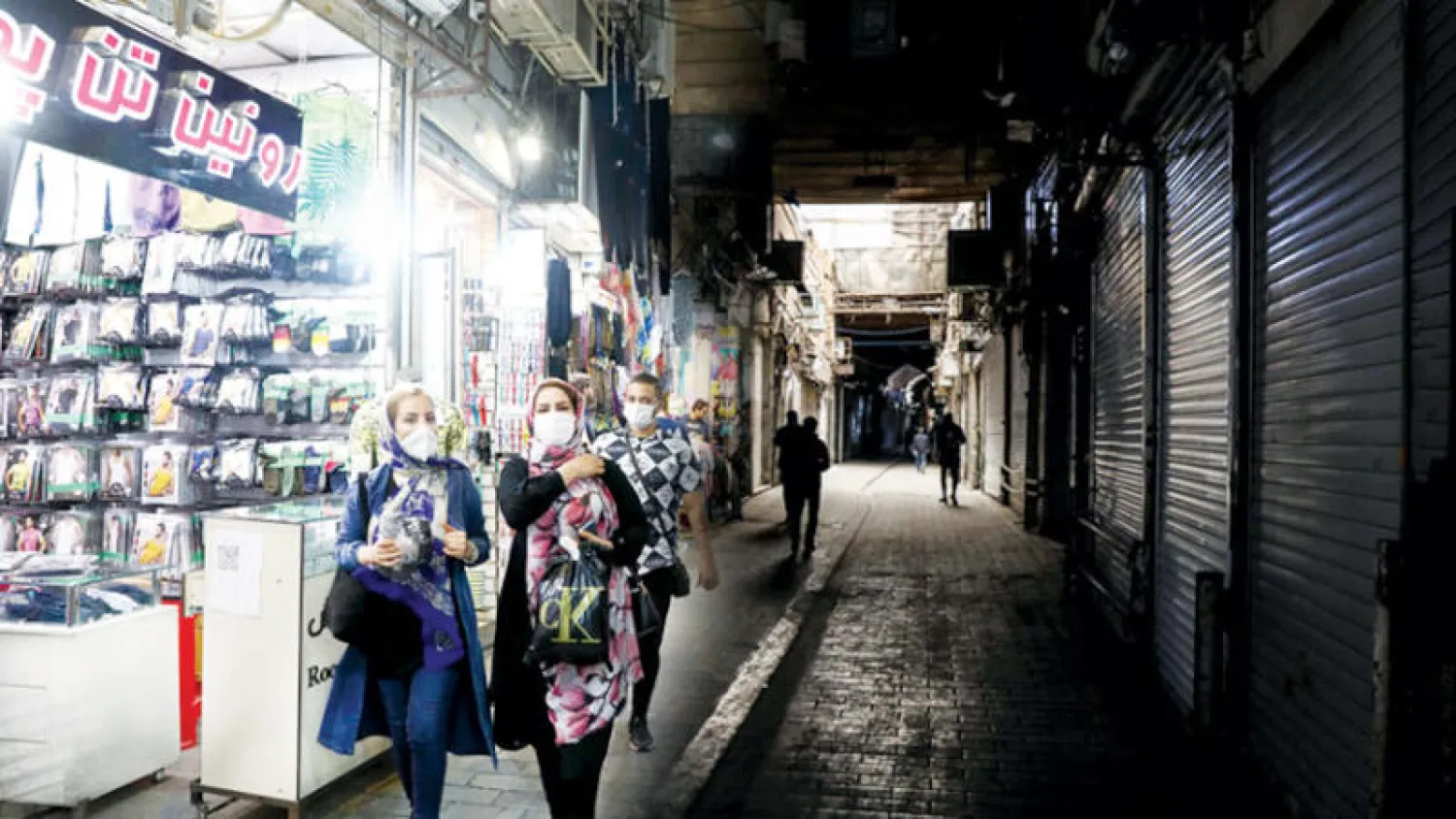 إيرانيتان تعبران من أمام متجر في بازار طهران القديم أمس (مهر)