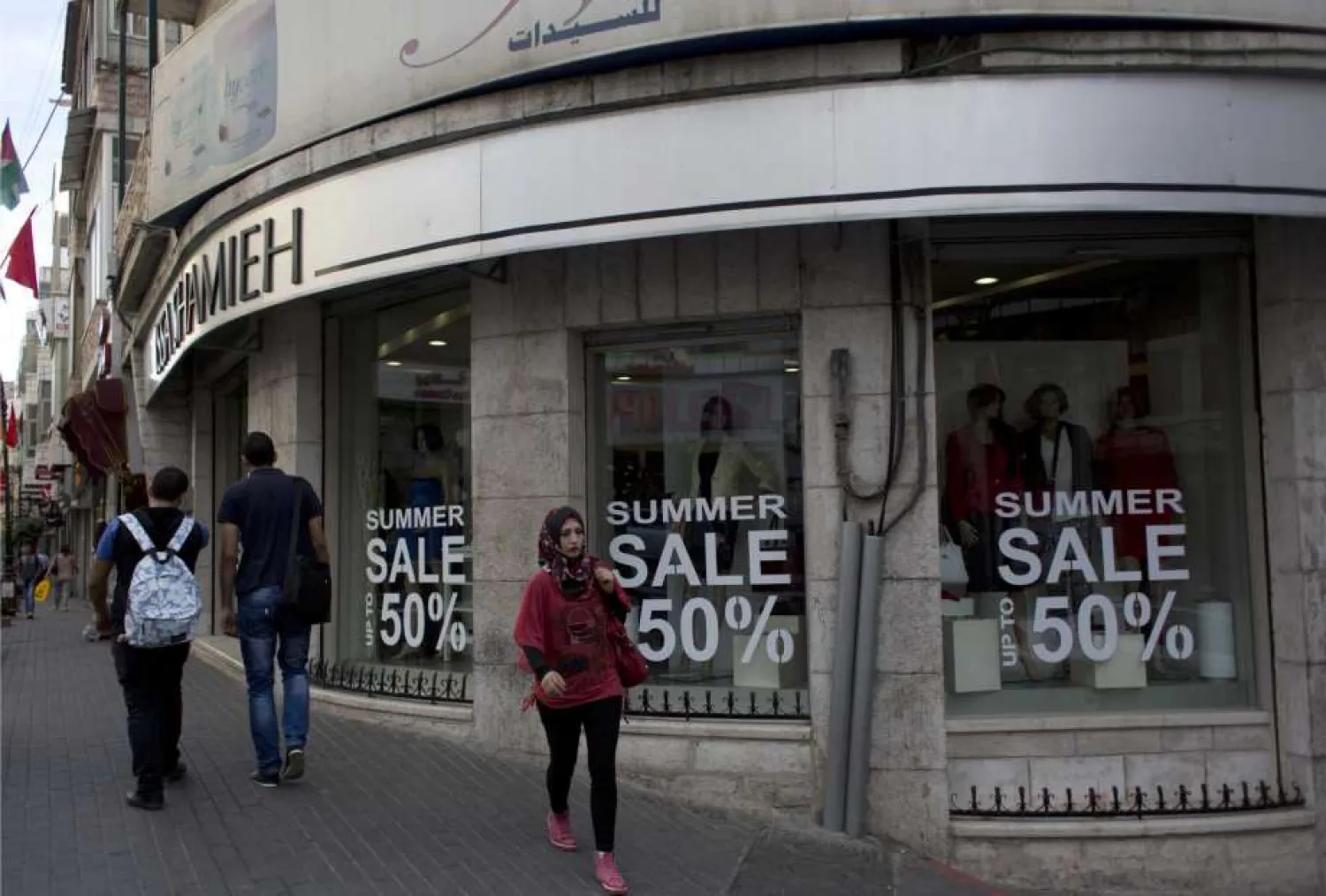 In this Sept. 29, 2015, file photo, Palestinians walk past a boutique in the West Bank city of Ramallah. (AP Photo/Nasser Nasser, File)