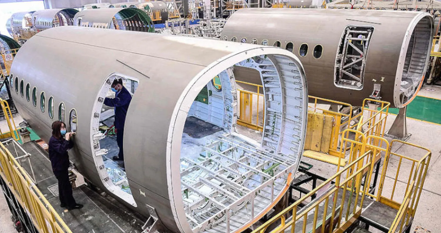 صينيون يعملون على جسم طائرة في مصنع بمقاطعة لياونينغ شمال شرقي الصين في 25 مايو (أ.ف.ب)