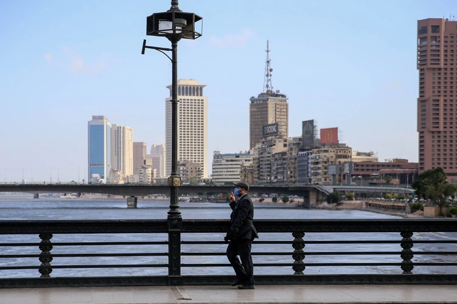 A mask-clad man walks along the Kasr el-Nil bridge connecting the island district of Zamalek to the city center of Cairo, May 24, 2020. (AFP)