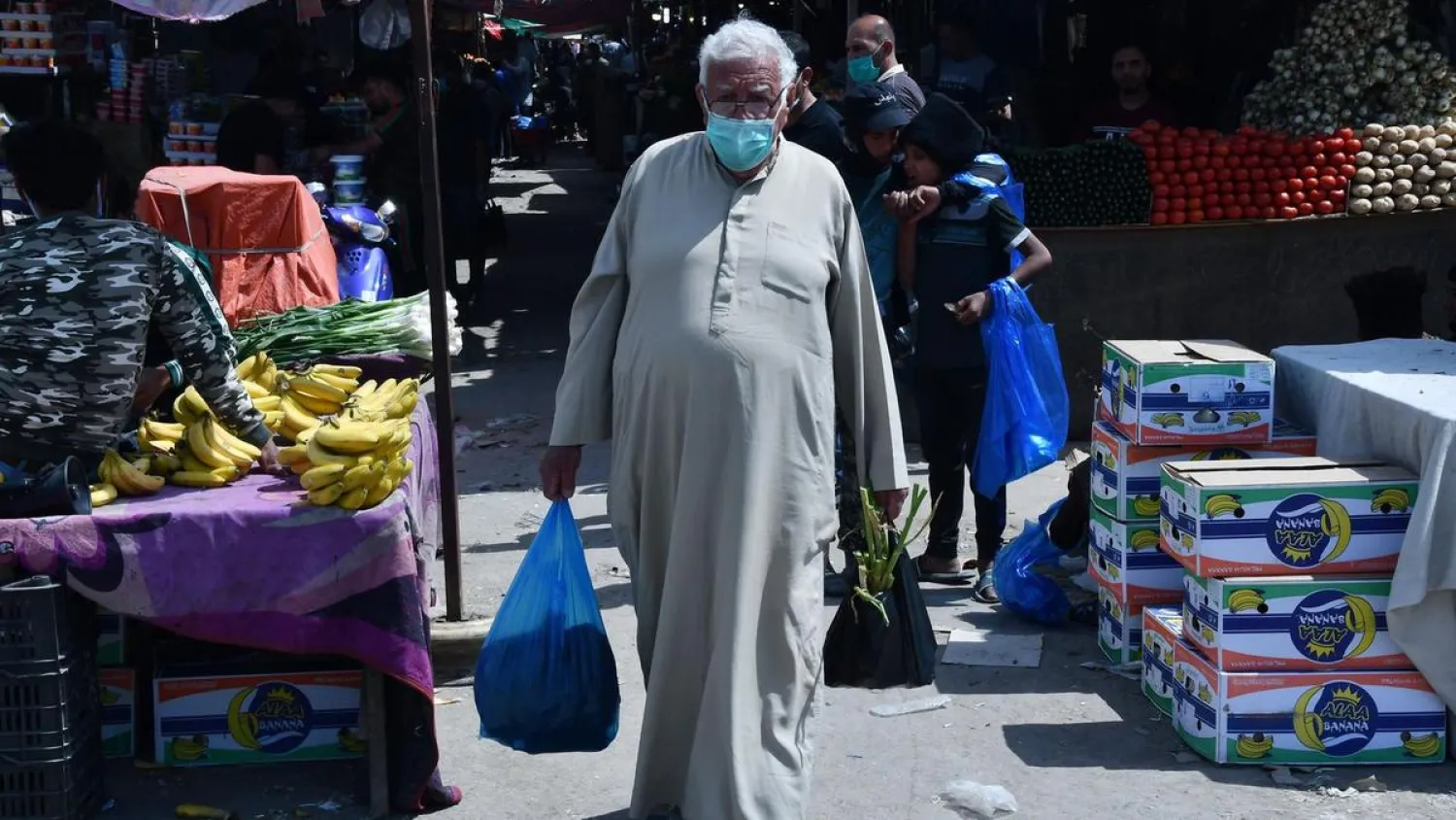 Iraqis wearing masks shop in the southern Iraqi city of Nassiriyah on March 25, 2020 amid the coronavirus pandemic. (AFP)