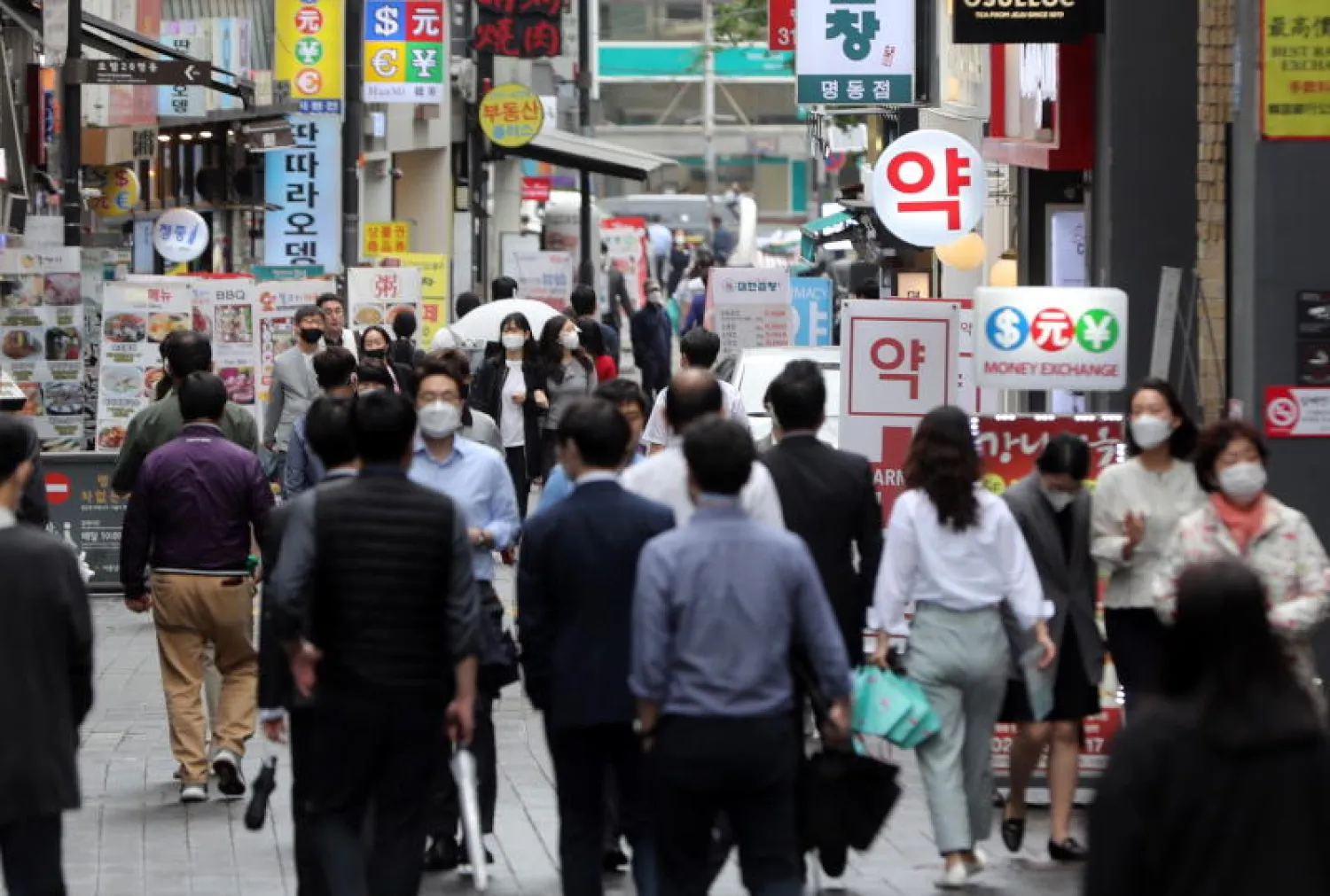 كوريون جنوبيون يسيرون في منطقة للتسوق وسط العاصمة سيول (إ.ب.أ)