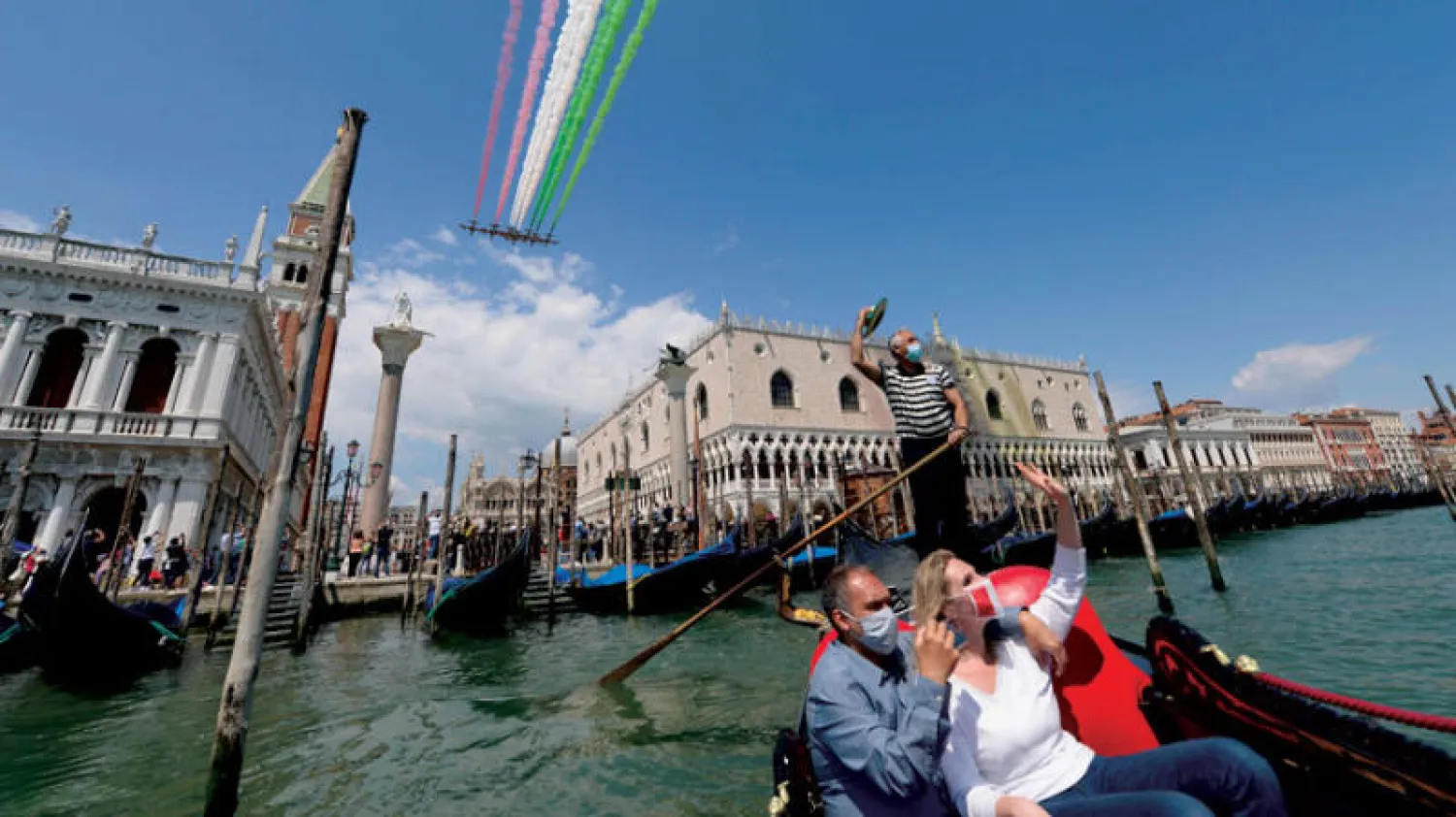 زوار فينيسيا بعد تقليص الحجر يضعون الكمامات حتى في الجندول (أ.ف.ب)