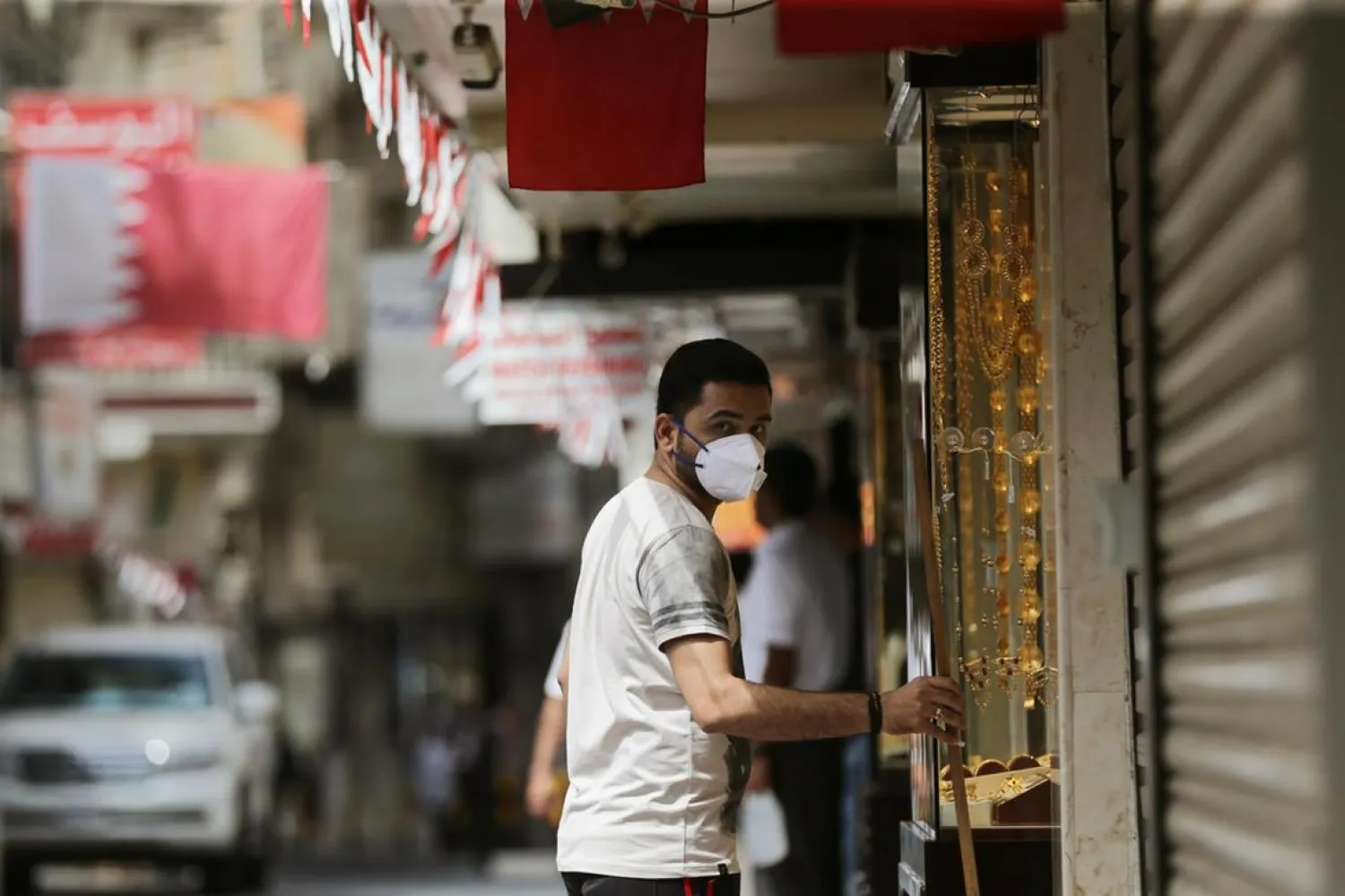 A man wearing a protective face mask stands in front of his gold jewelery shop in a street of Manama, Bahrain. (EPA)