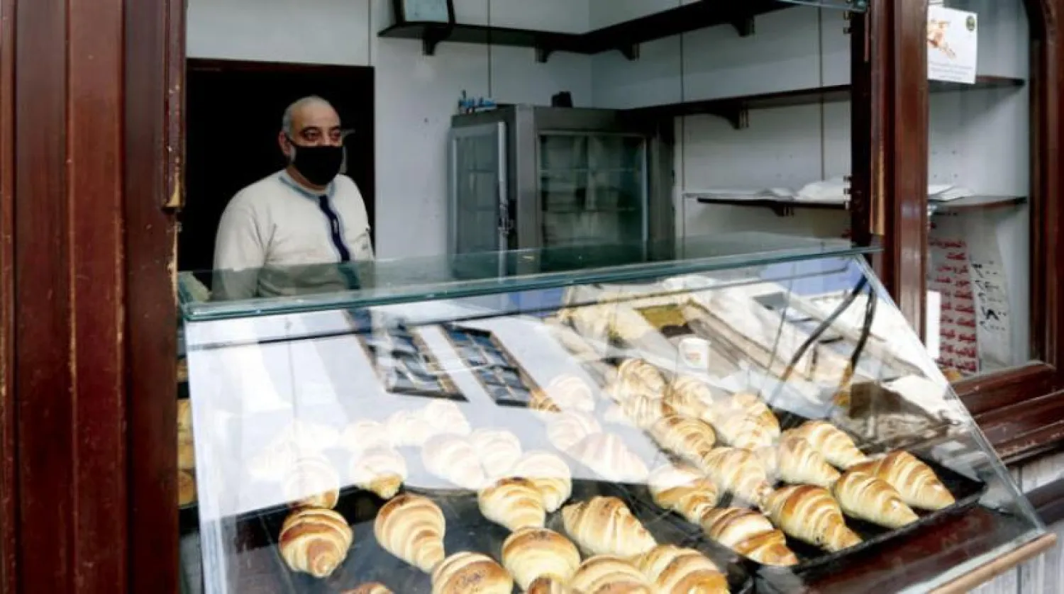 A Syrian man, wearing a protective face mask and gloves to protect against the coronavirus (COVID-19) pandemic, waits for customers at his bakery in the Qaymariyya quarter of the Old City of the capital Damascus on April 14, 2020. (Photo by LOUAI BESHARA / AFP)