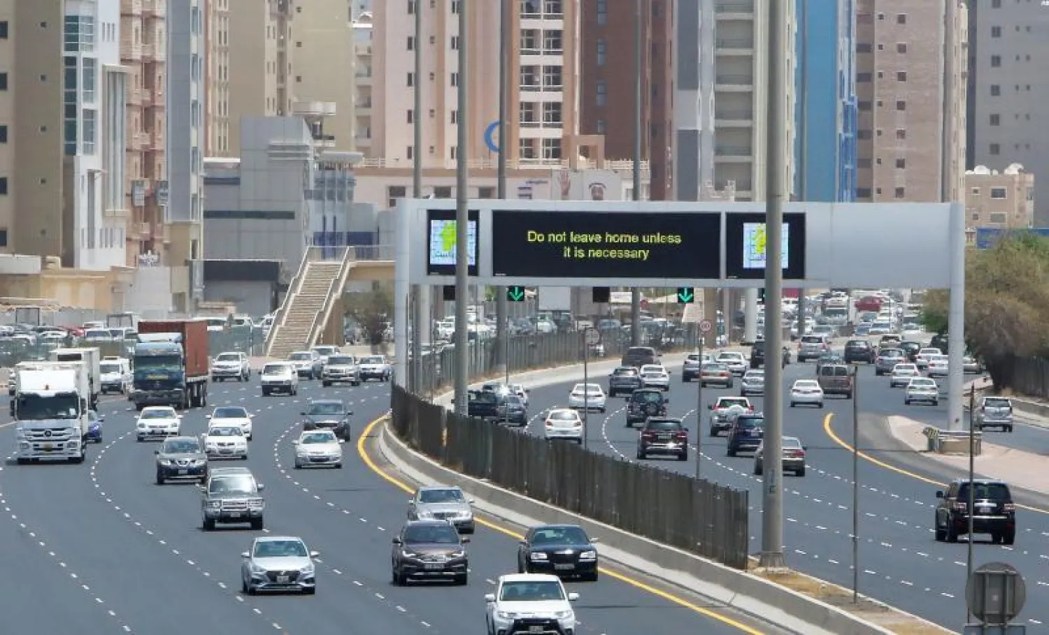 لافتة تذكّر السكان باليقظة وهم يسيرون على طول طريق سريع في الكويت العاصمة (أ.ف.ب)
