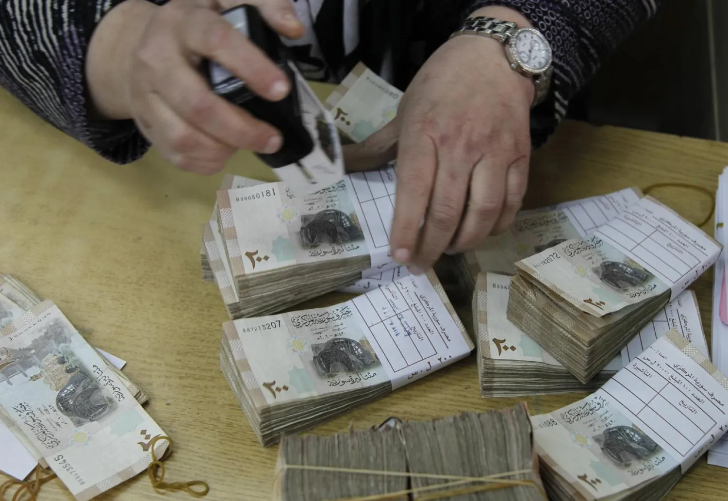 An employee stamps stacks of Syrian pound notes at the Syrian central bank in Damascus April 23, 2013. (Reuters)