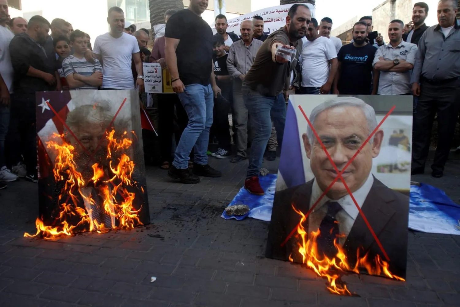Palestinians burn pictures of US President Donald Trump, left, and Israeli Prime Minister Benjamin Netanyahu during a protest against Trump's mideast initiative, in the West Bank city of Nablus, Saturday, May 30, 2020.(AP Photo/Majdi Mohammed)