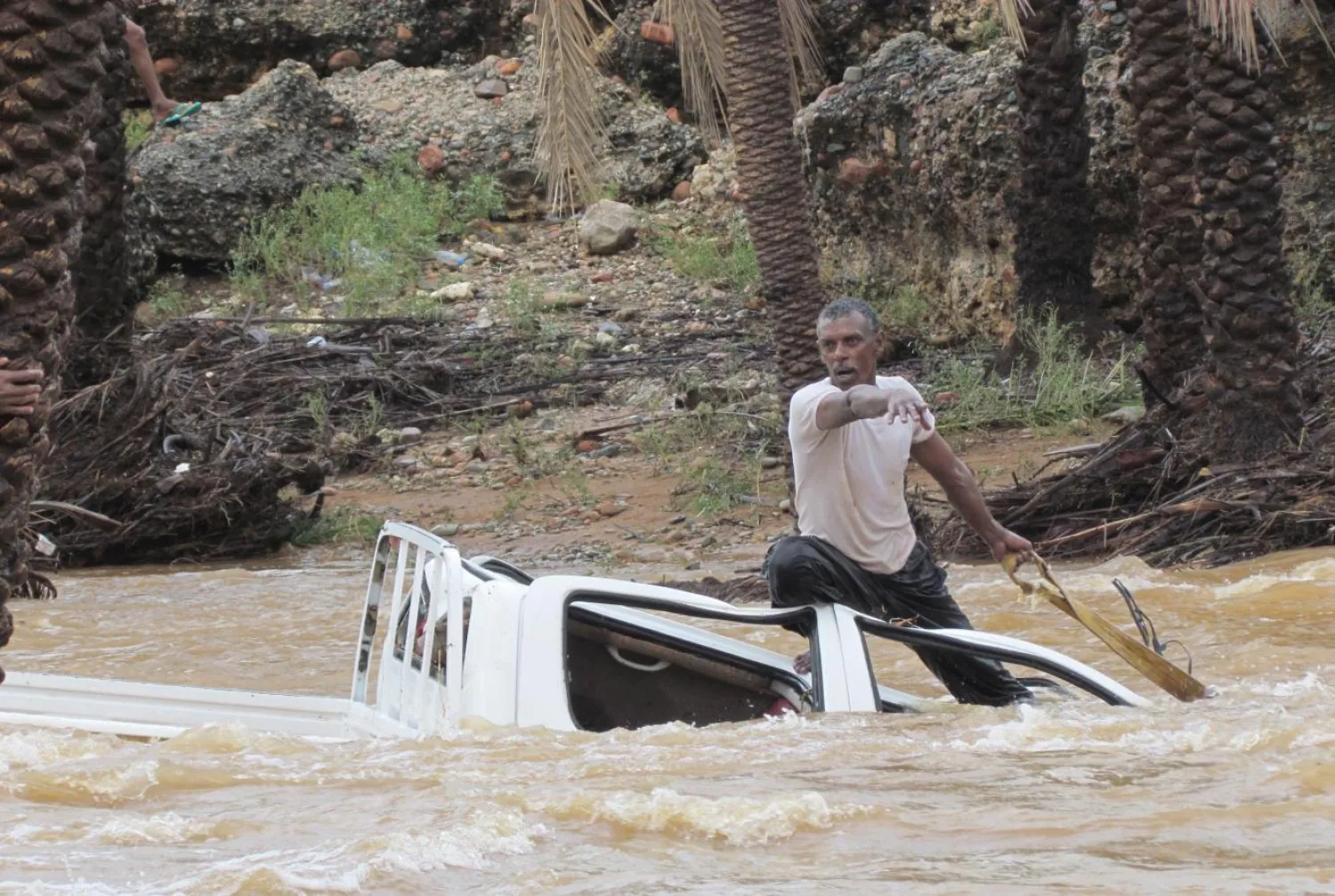 A man gestures as he tries to save a vehicle swept away by flood waters in Yemen. Reuters file photo