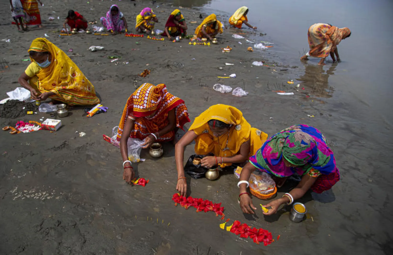 نساء هنديات يمارسن طقوساً هندوسية في نهر براهامابوترا إبعاداً لخطر الفيروس (أ.ب)