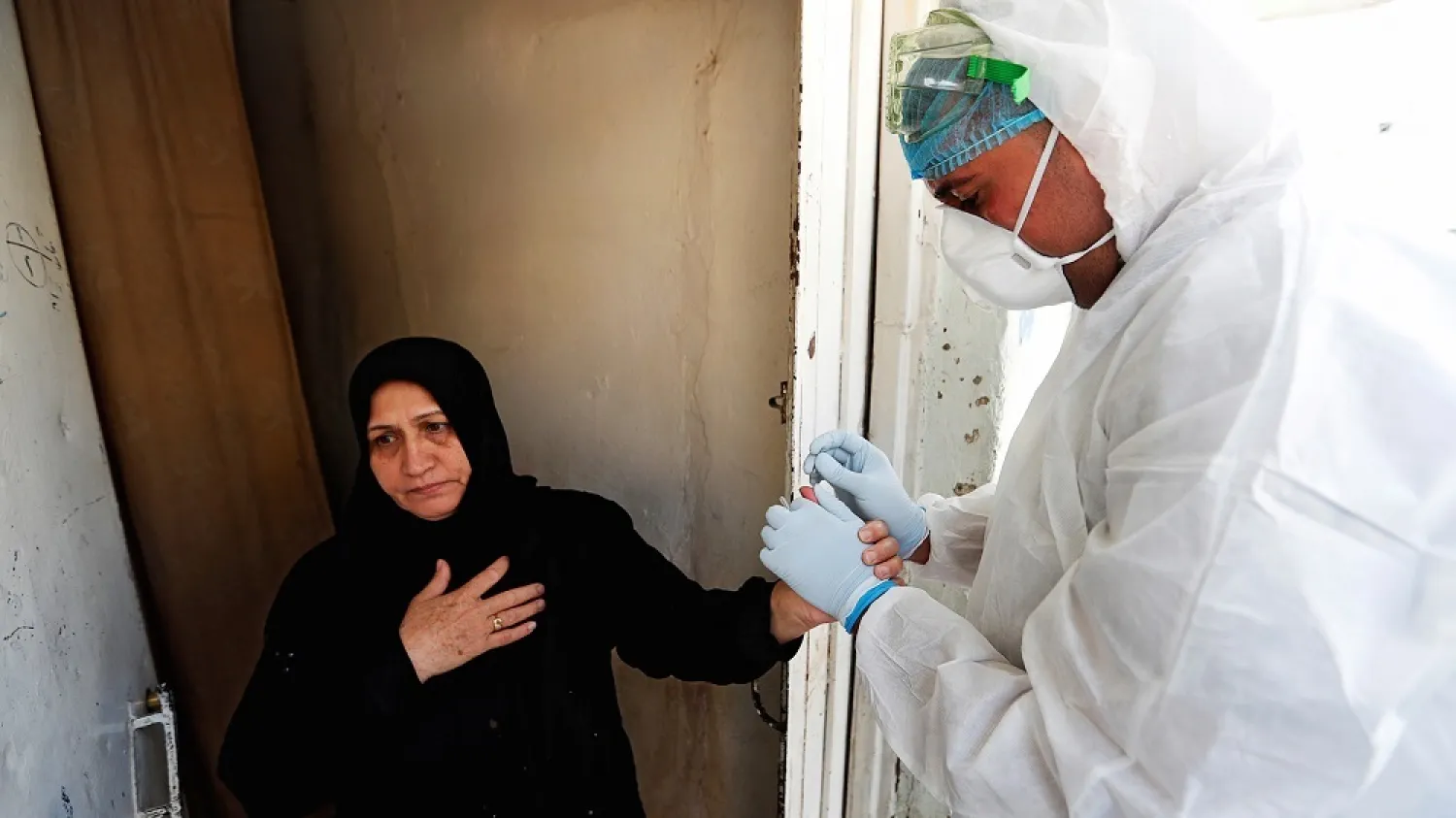 A health care worker takes blood samples from a woman during testing for the coronavirus in the Sadr City district of Baghdad, May 21, 2020. (Reuters)