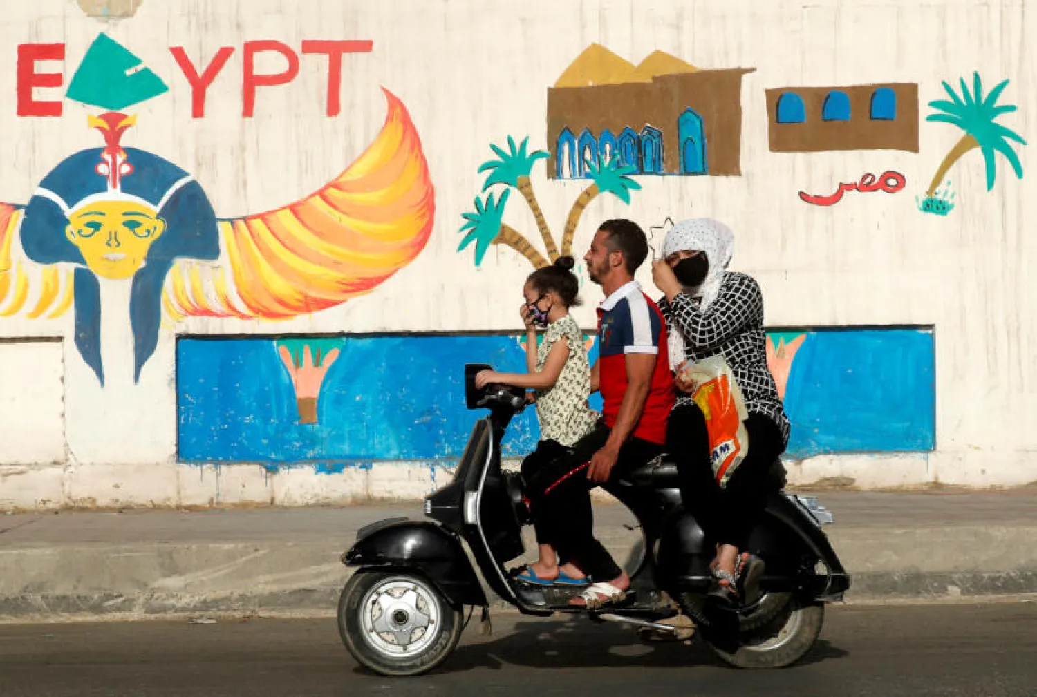 رجل وأسرته يرتدون الكمامات على دراجة بخارية في القاهرة (رويترز)
