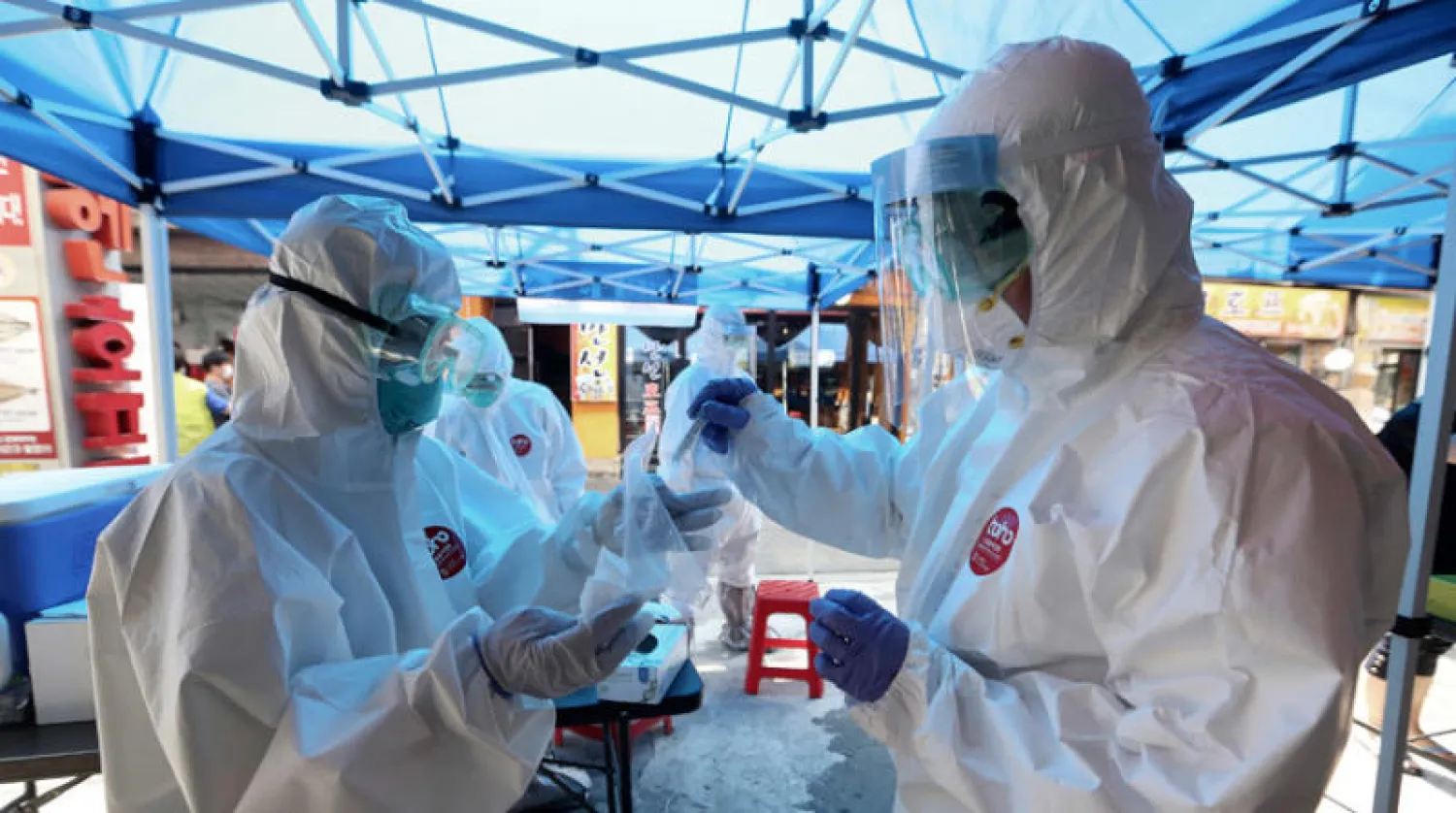 عاملا صحة كوريان جنوبيان يحفظان عينة دم أحد المشتبه بإصابتهم في سيول الجمعة (إ.ب.أ)