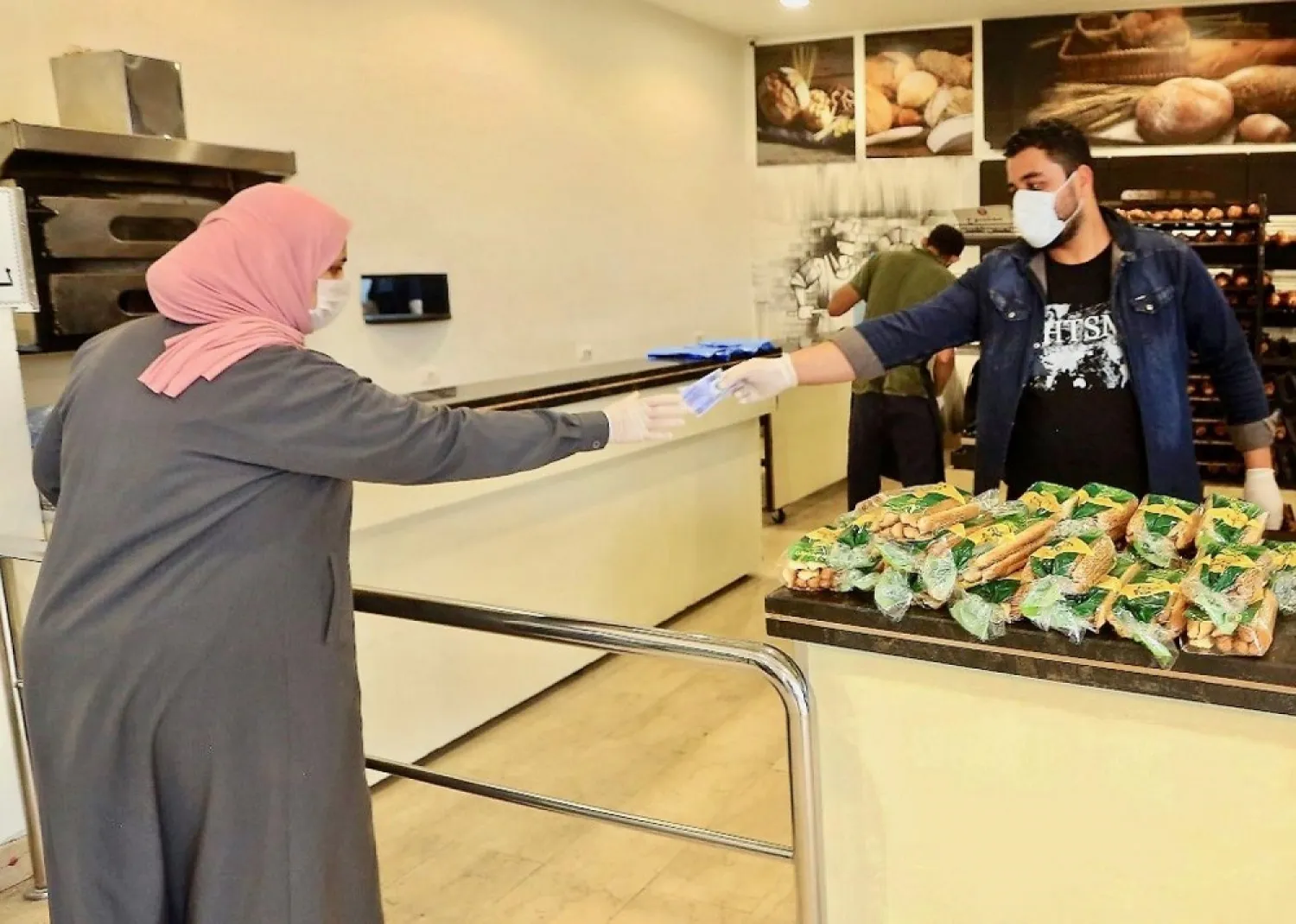 A customer pays from behind a barrier amid concerns over the spread of the coronavirus at a supermarket in the Libyan capital, Tripoli. (AFP)