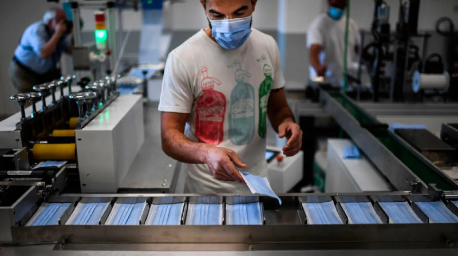 عامل يشرف على إنتاج أقنعة في مصنع قرب لشبونة (أ.ف.ب)