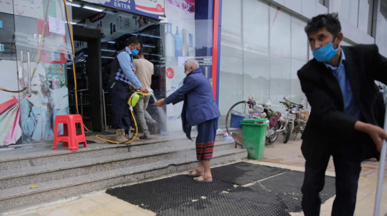 رجل يعقم الزوار أمام أحد متاجر صنعاء (أ.ب)