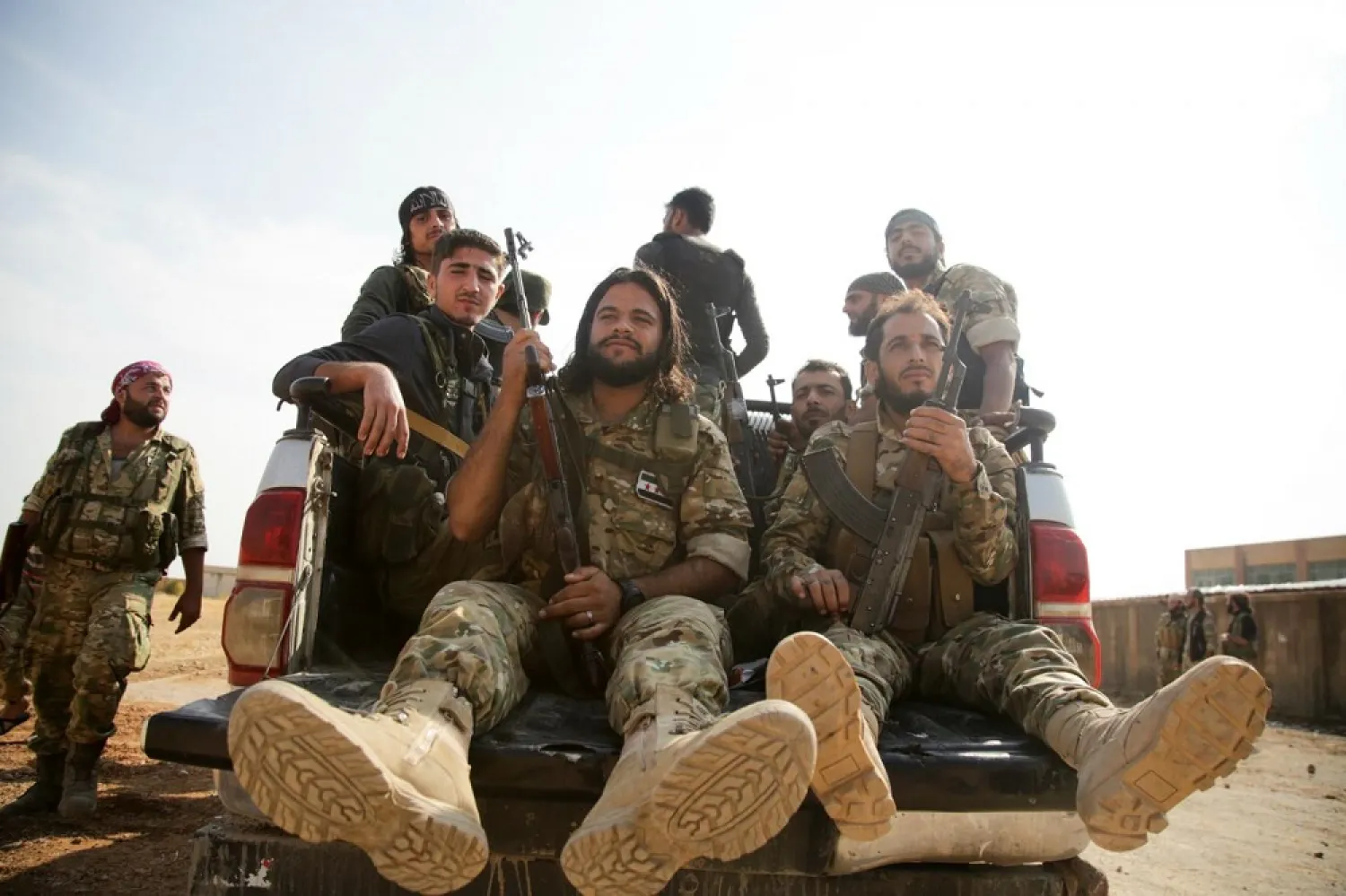 Turkey-backed Syrian fighters gather on a road between the northern Syrian towns of Tal Abyad and Kobane. (AFP)