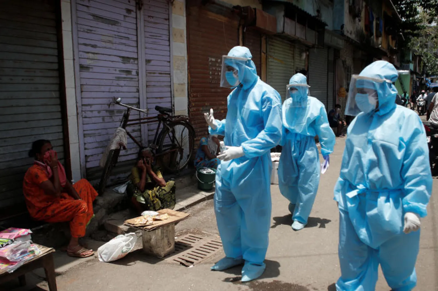 ممارسون صحيون يرتدون بدلات واقية يقدمون إرشادات للسكان عن مرض كورونا في مومباي (رويترز)