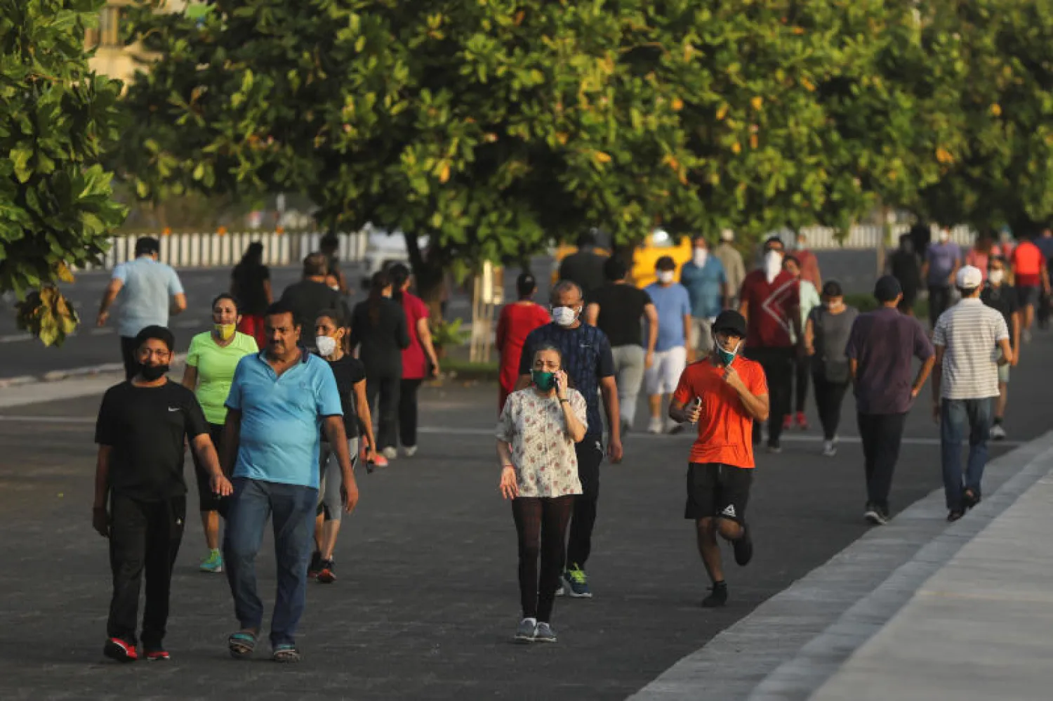 أشخاص يسيرون في أحد متنزهات مومباي (رويترز)