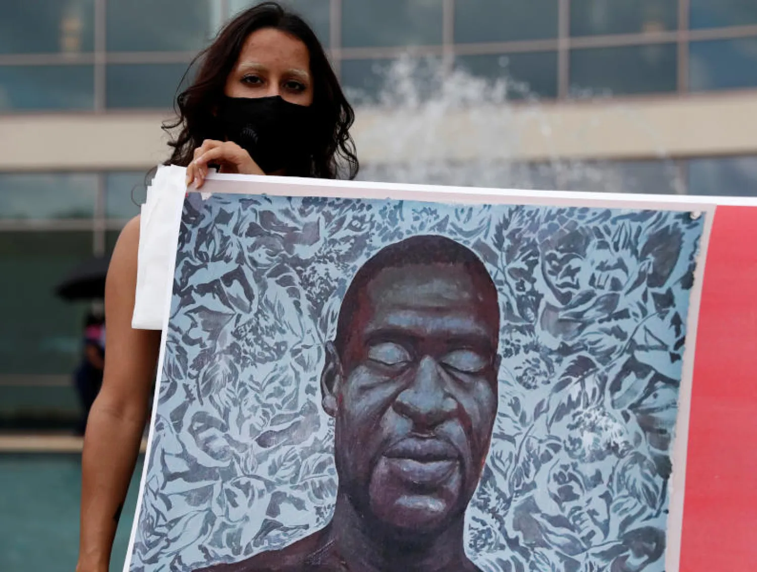 امرأة تحمل لافتة لجورج فلويد في هيوستن بتكساس (رويترز)